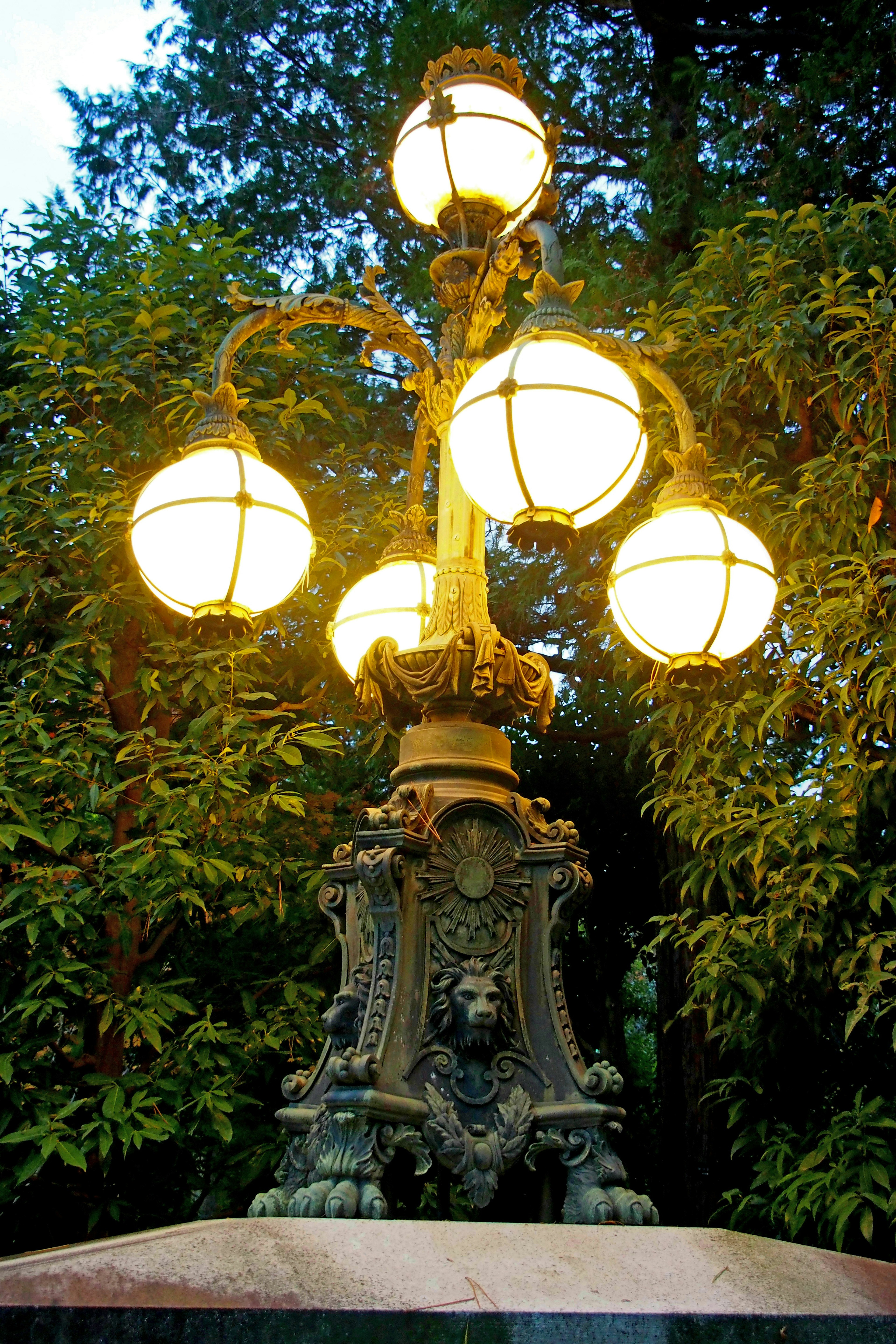 Elegant street lamp design with glowing globes surrounded by lush green trees