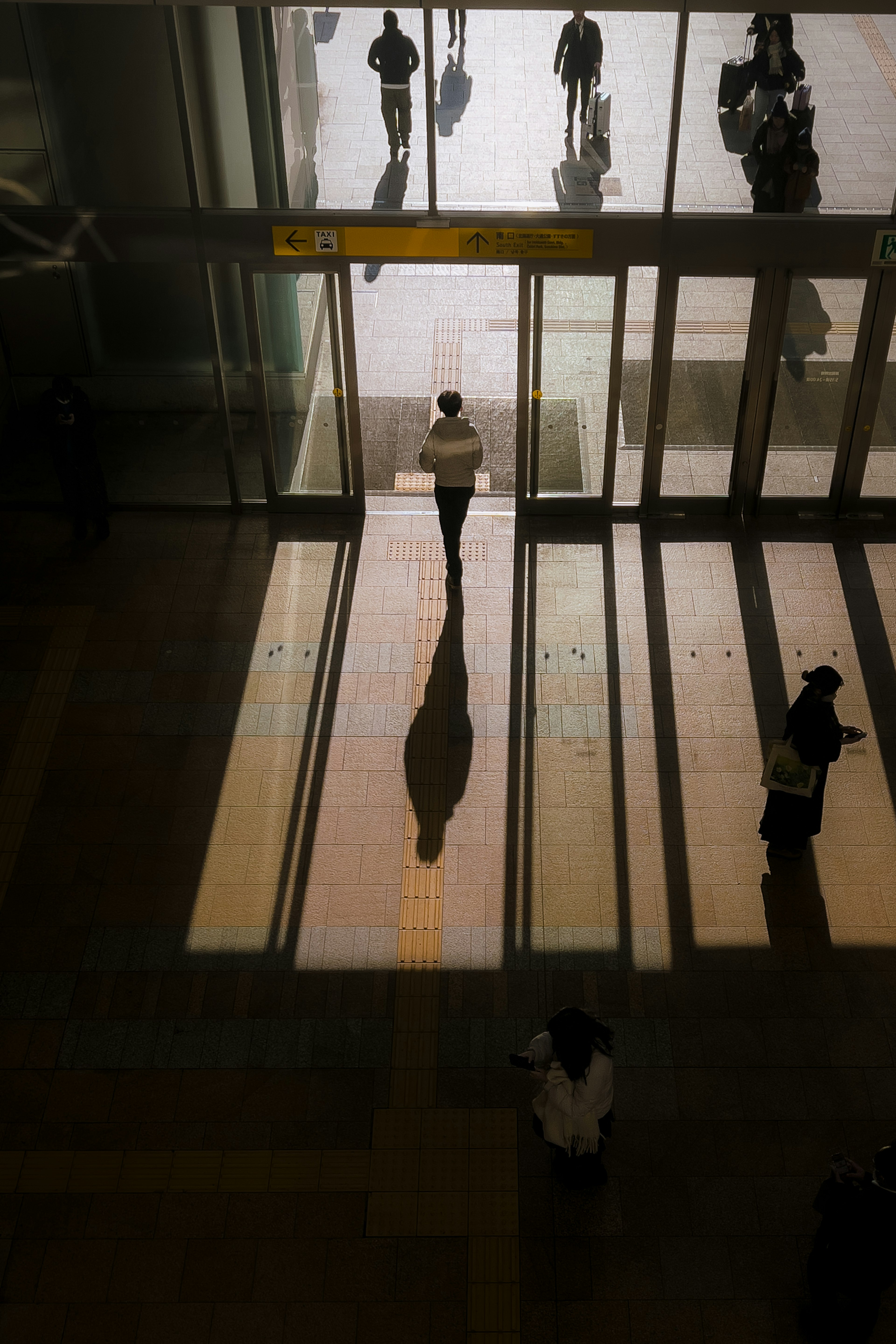 A silhouette of a person walking towards the entrance with shadows on the floor