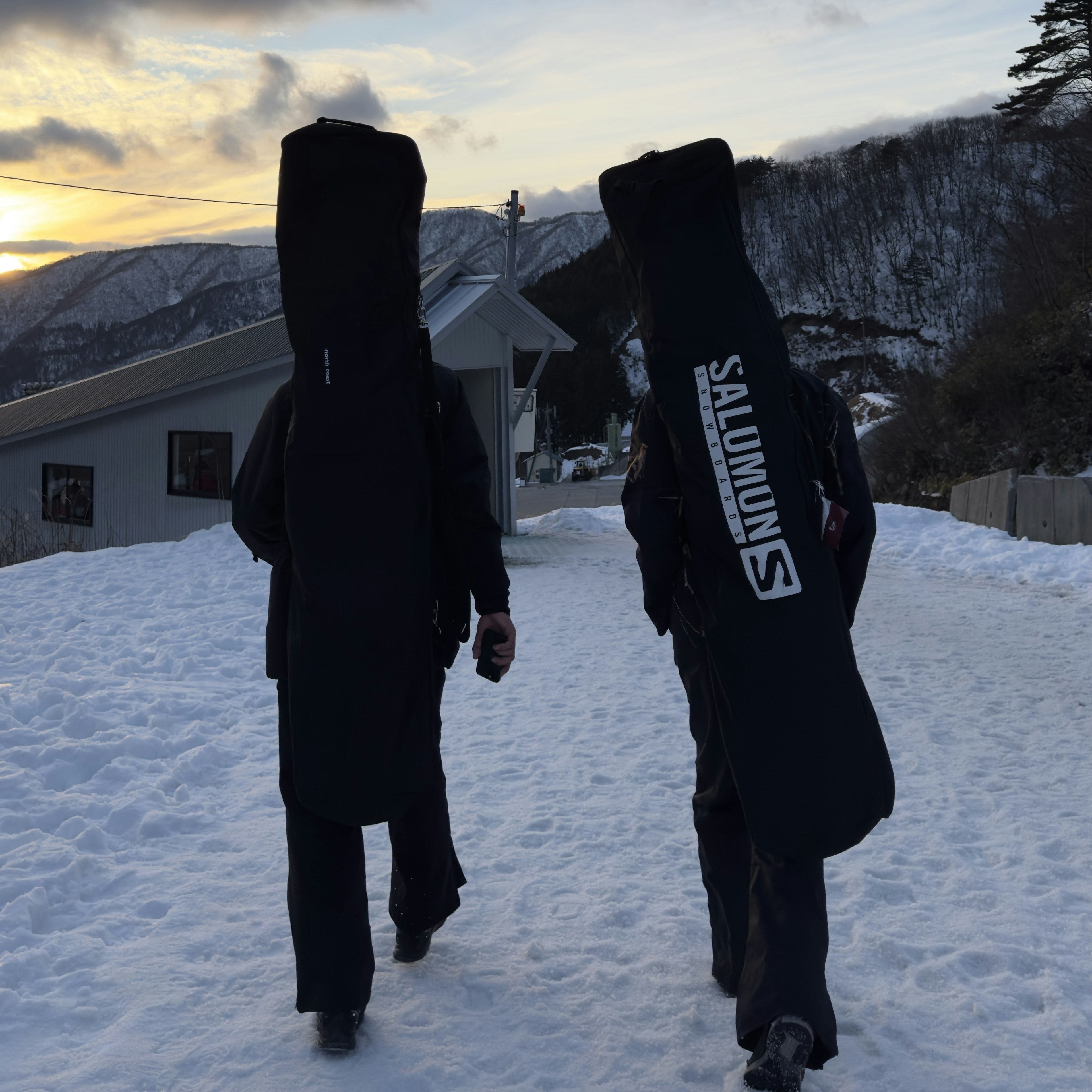 雪の中を歩く二人のスキーヤーがスキー板を担いでいる風景