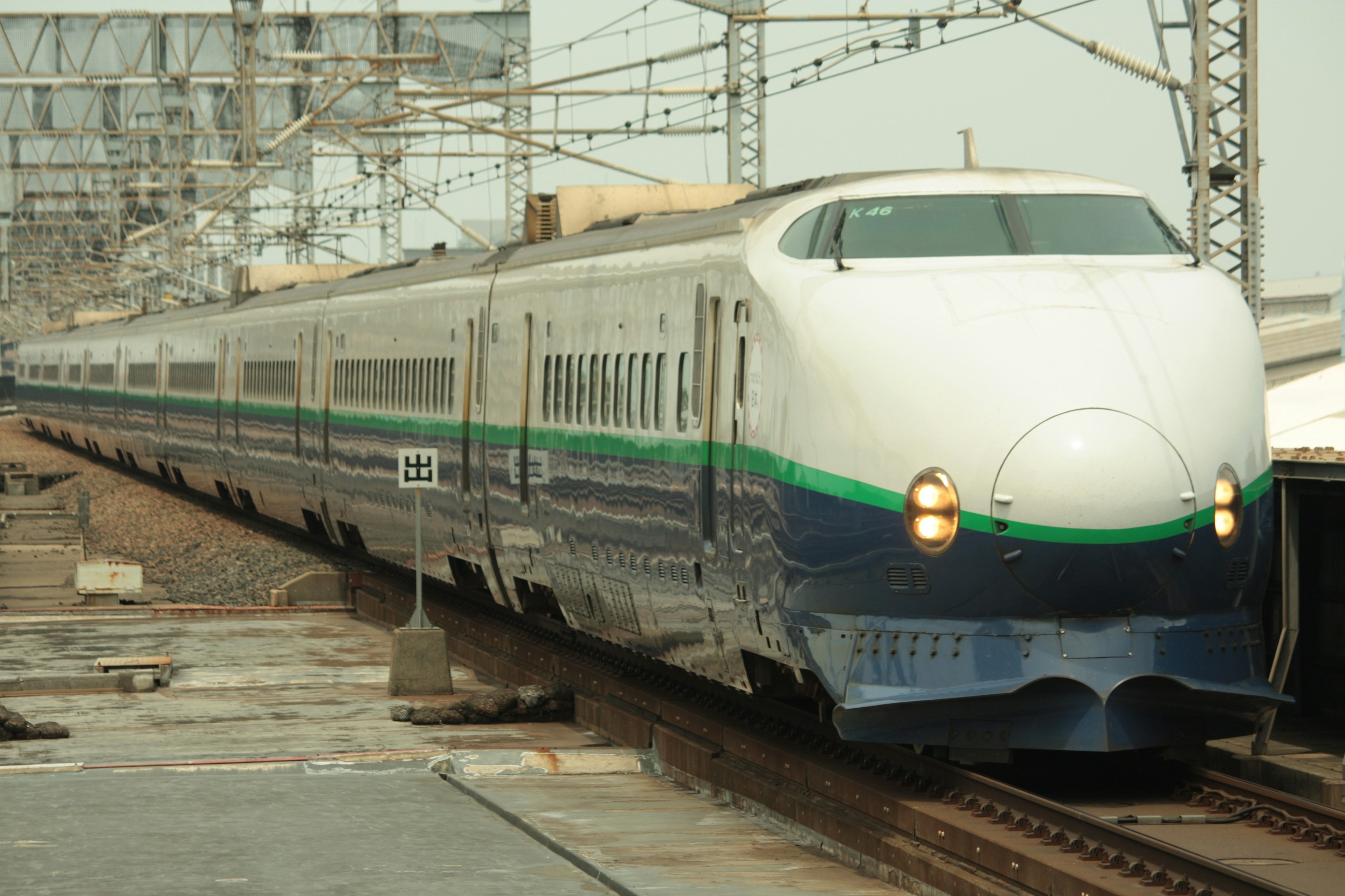 Kereta Shinkansen berwarna biru dan hijau melintas di rel kereta