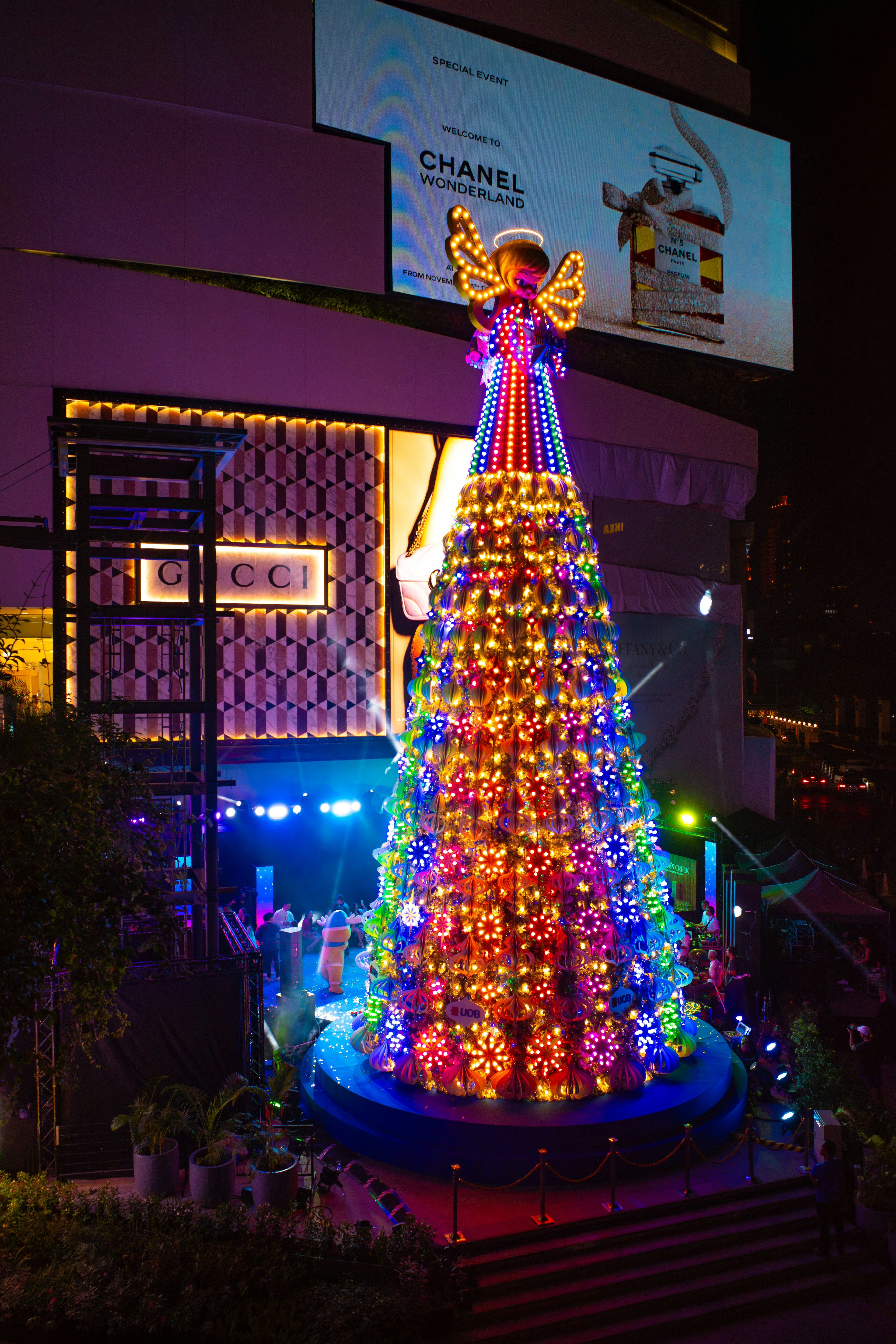 Pohon Natal yang hidup diterangi di malam hari dengan dekorasi malaikat