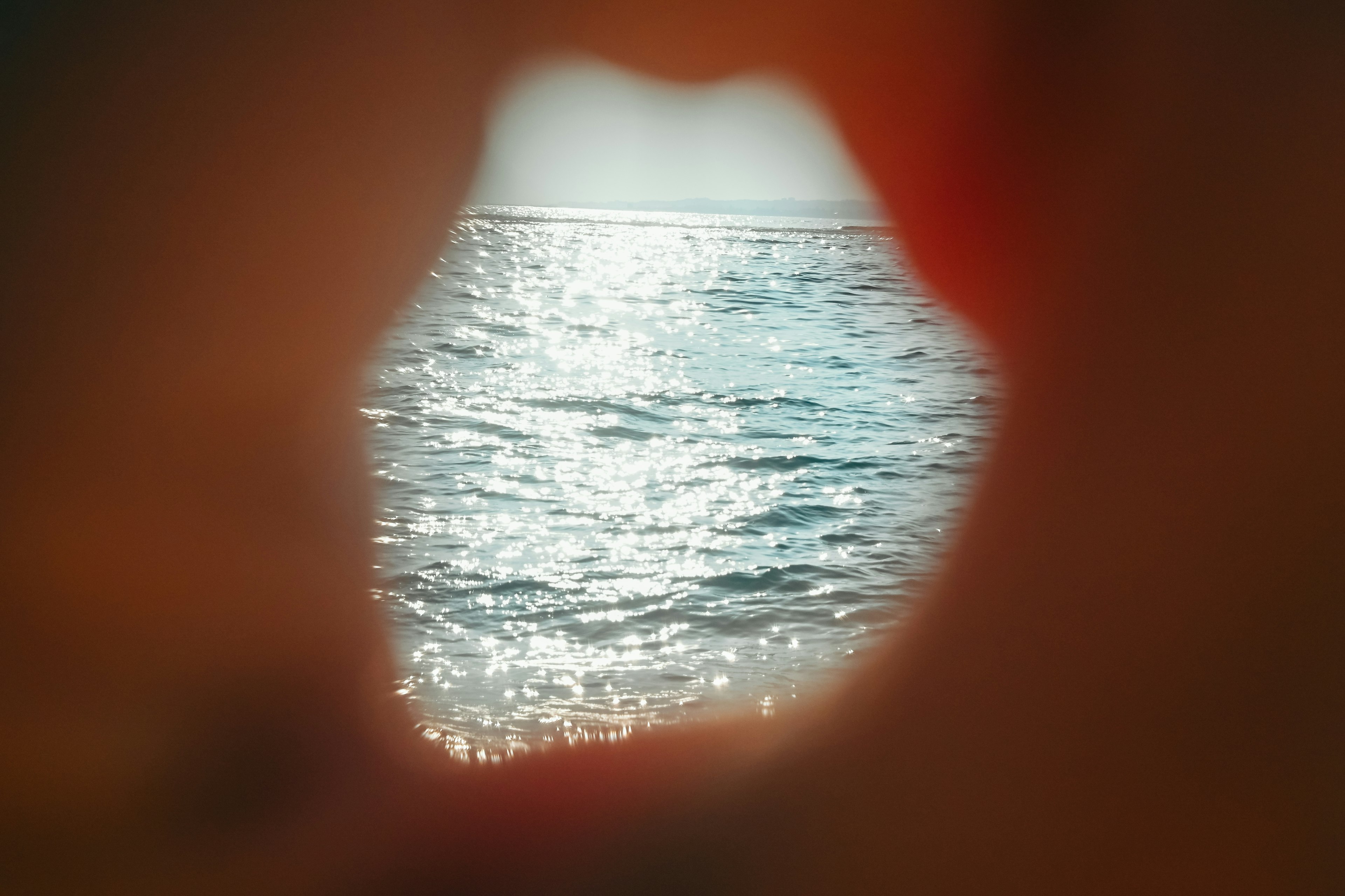 海を見つめる形の穴越しの眺め 光が反射する水面が印象的