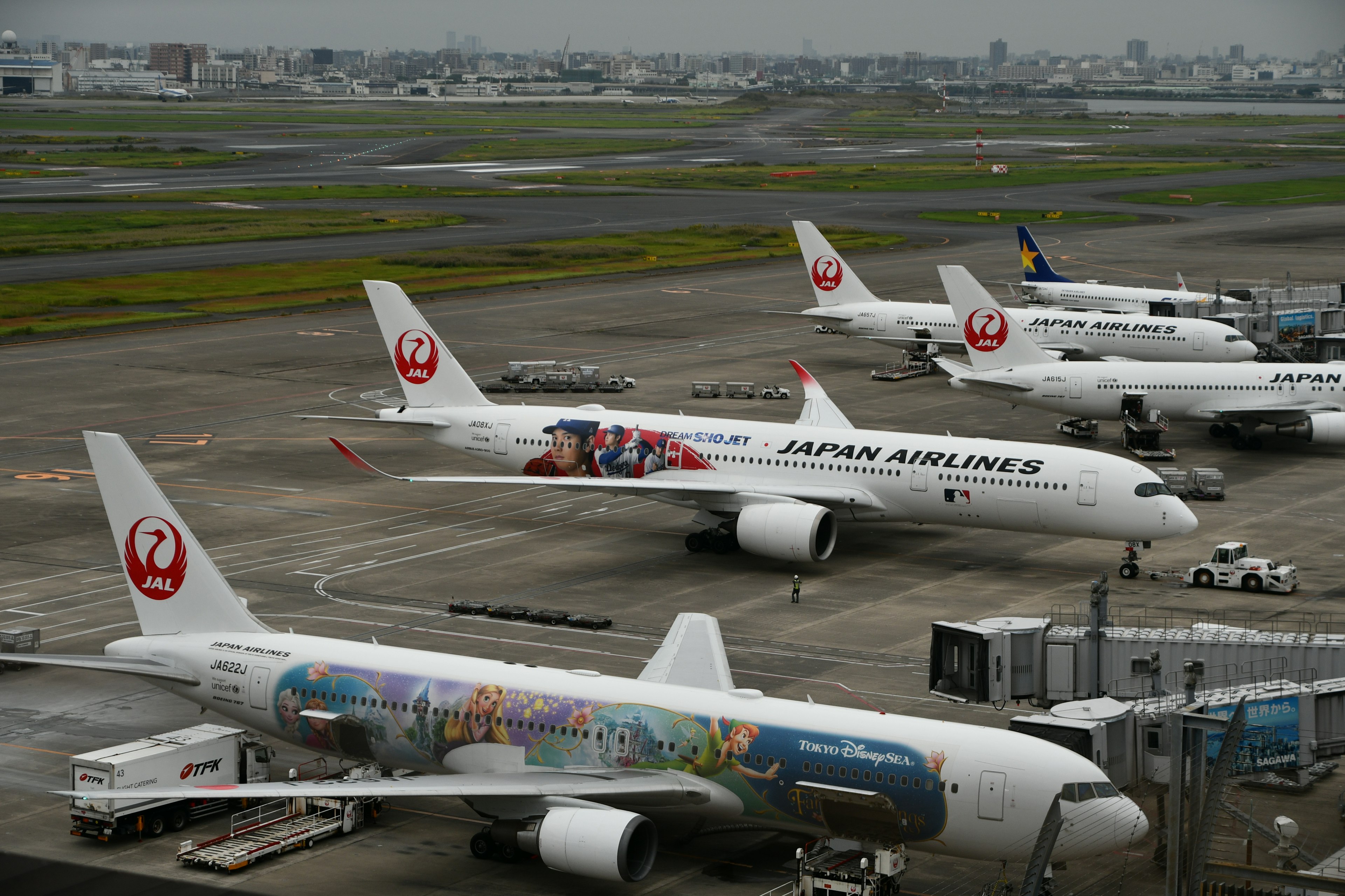 日本航空的飞机停在机场，天空多云