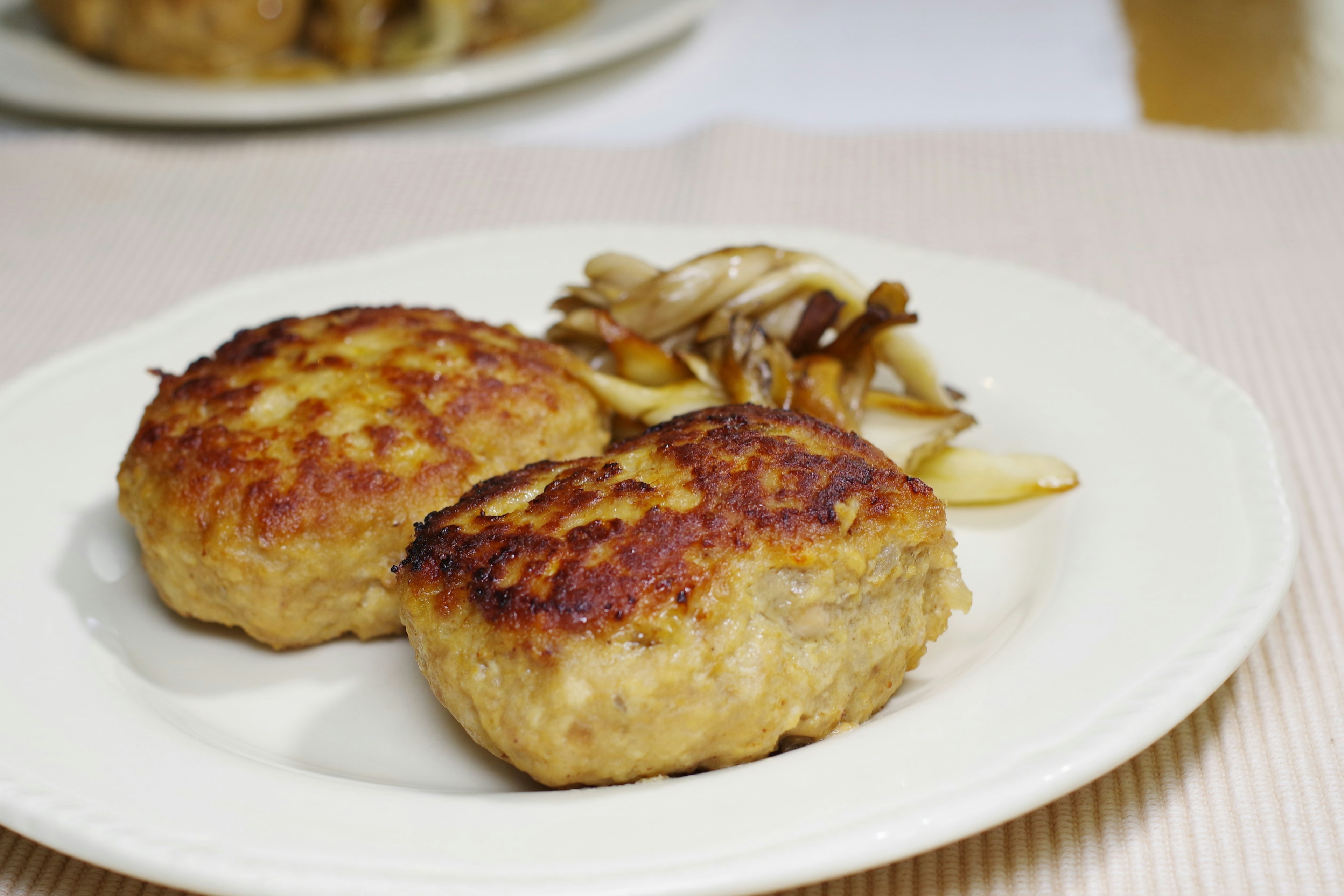 Two grilled meat patties served with sautéed mushrooms