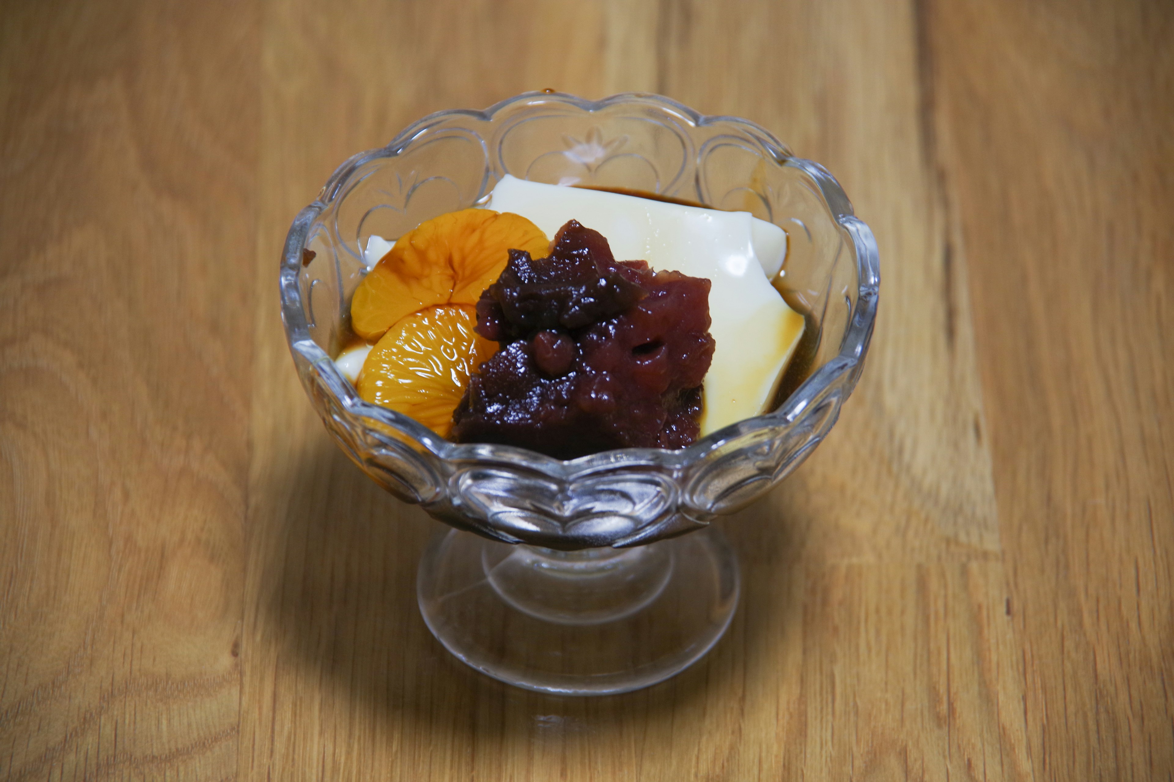 Dessert in einer Glasschüssel mit weißer Sahne roter Bohnenpaste und Orangenscheiben