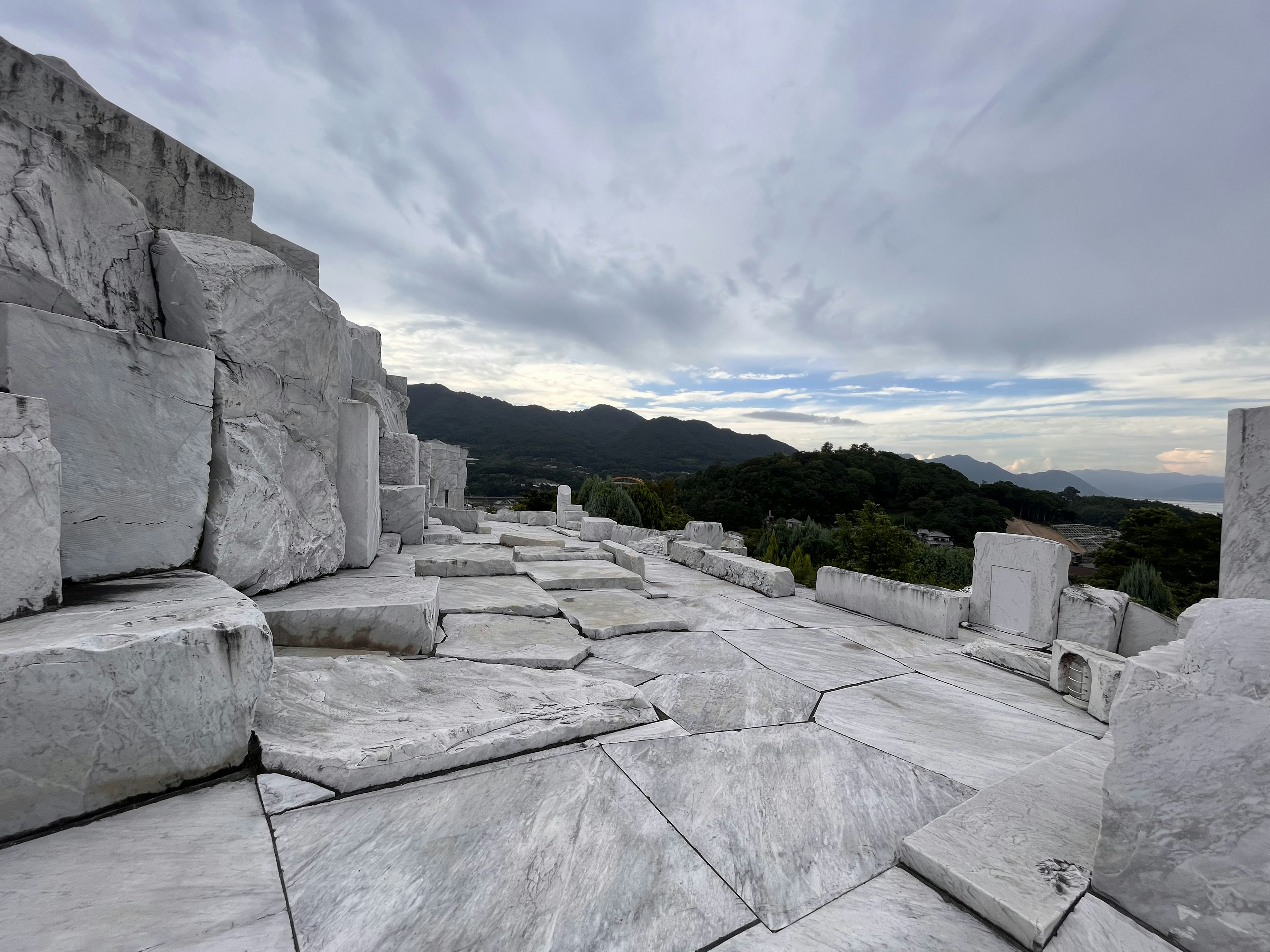 Vista de una cantera de mármol con grandes bloques de piedra y cielo nublado