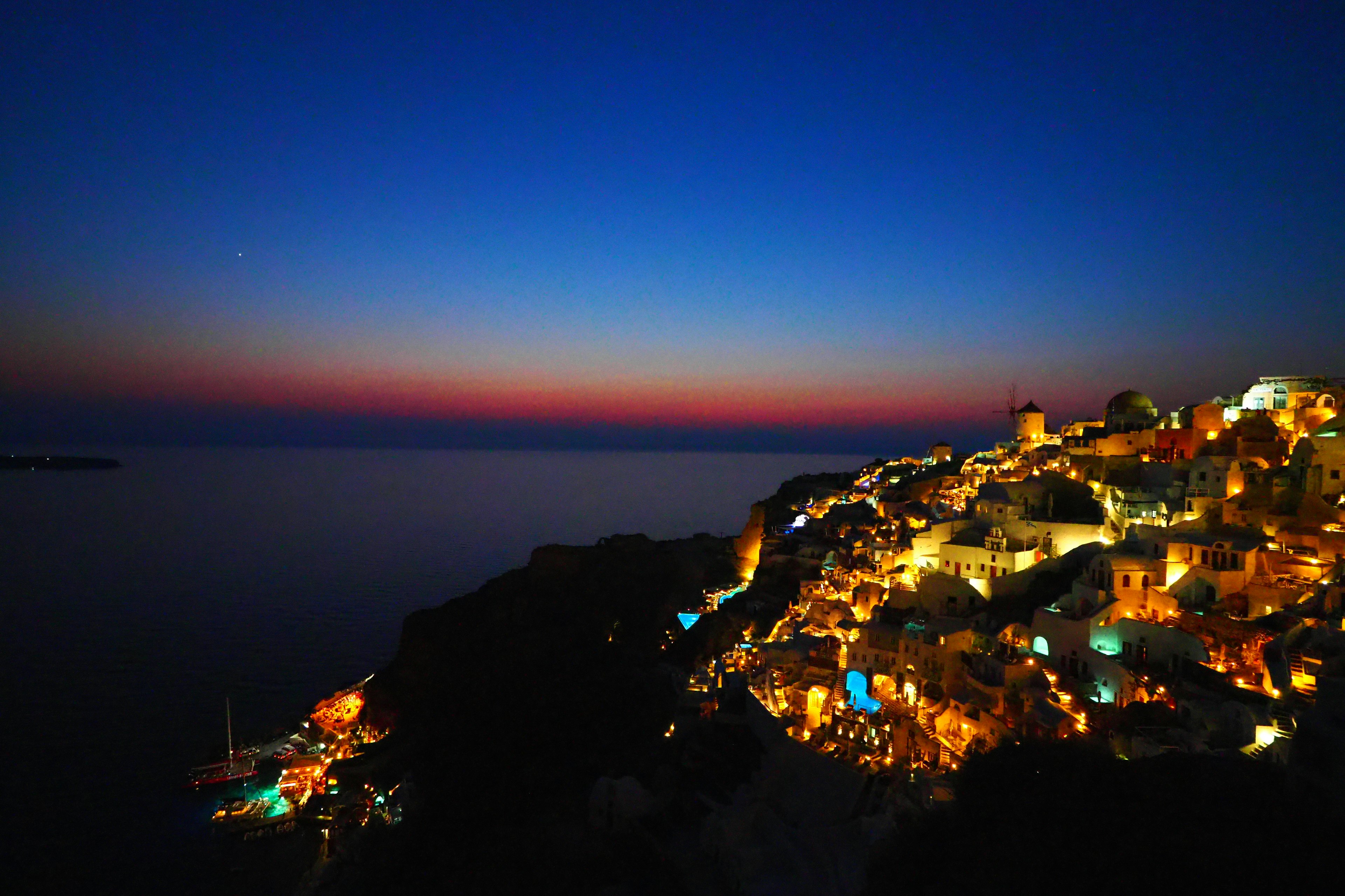 Beautiful night view of a coastal town surrounded by blue sky and sunset ocean