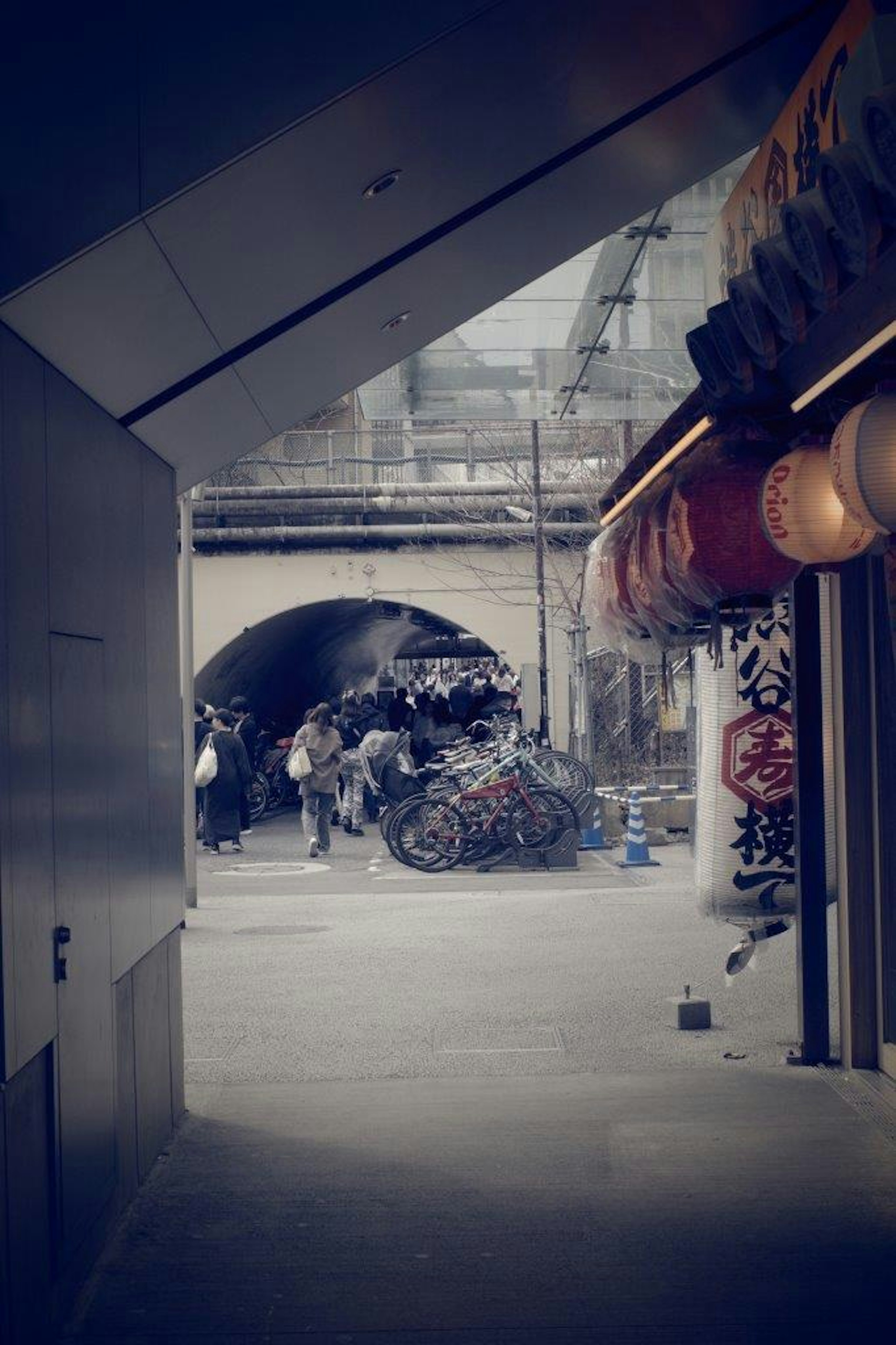 狭い通路の先にあるアーチ型の橋と屋台の風景