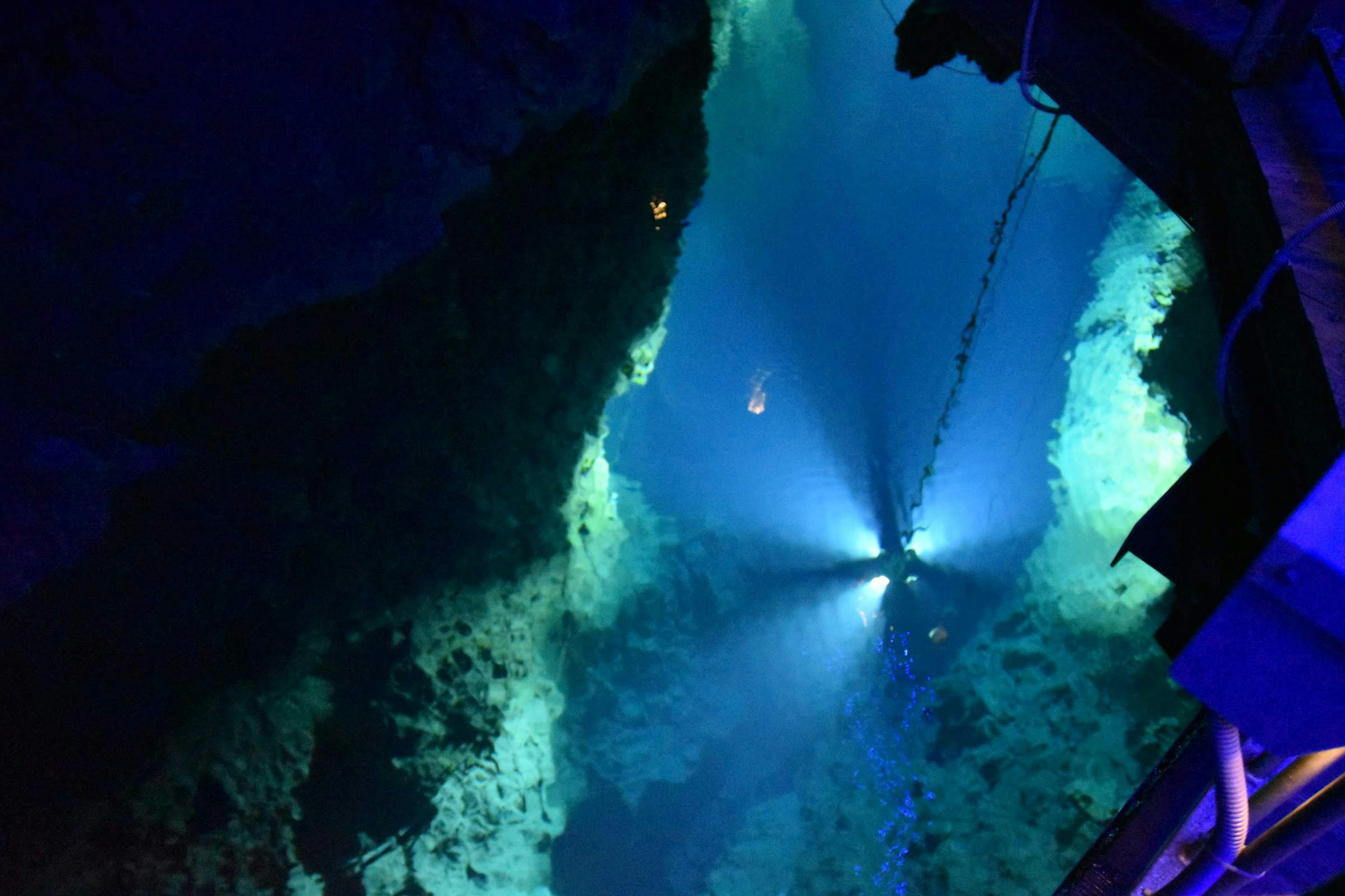 Image of a deep underwater canyon with blue light beams