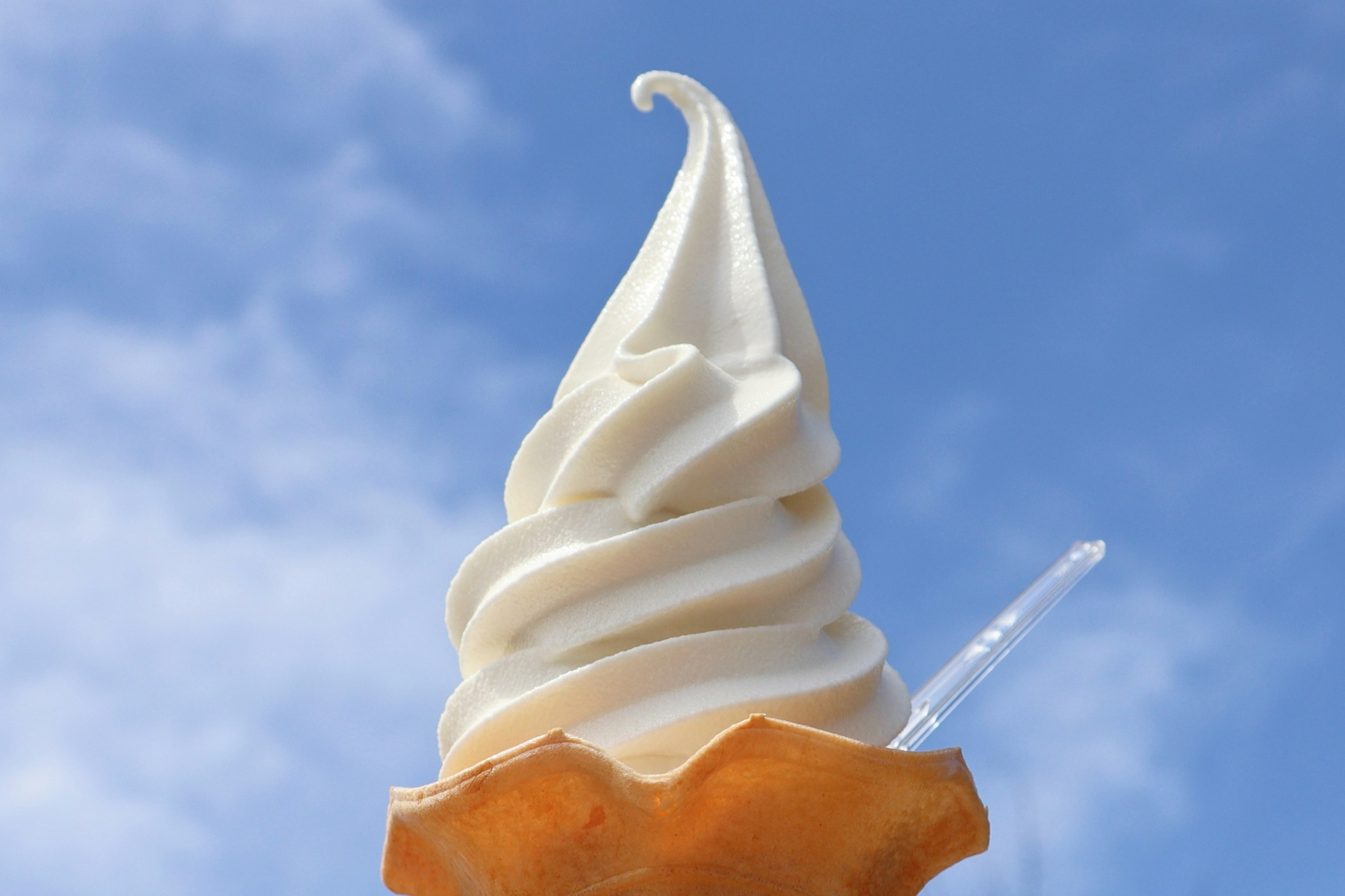 Creamy soft serve ice cream cone against a blue sky