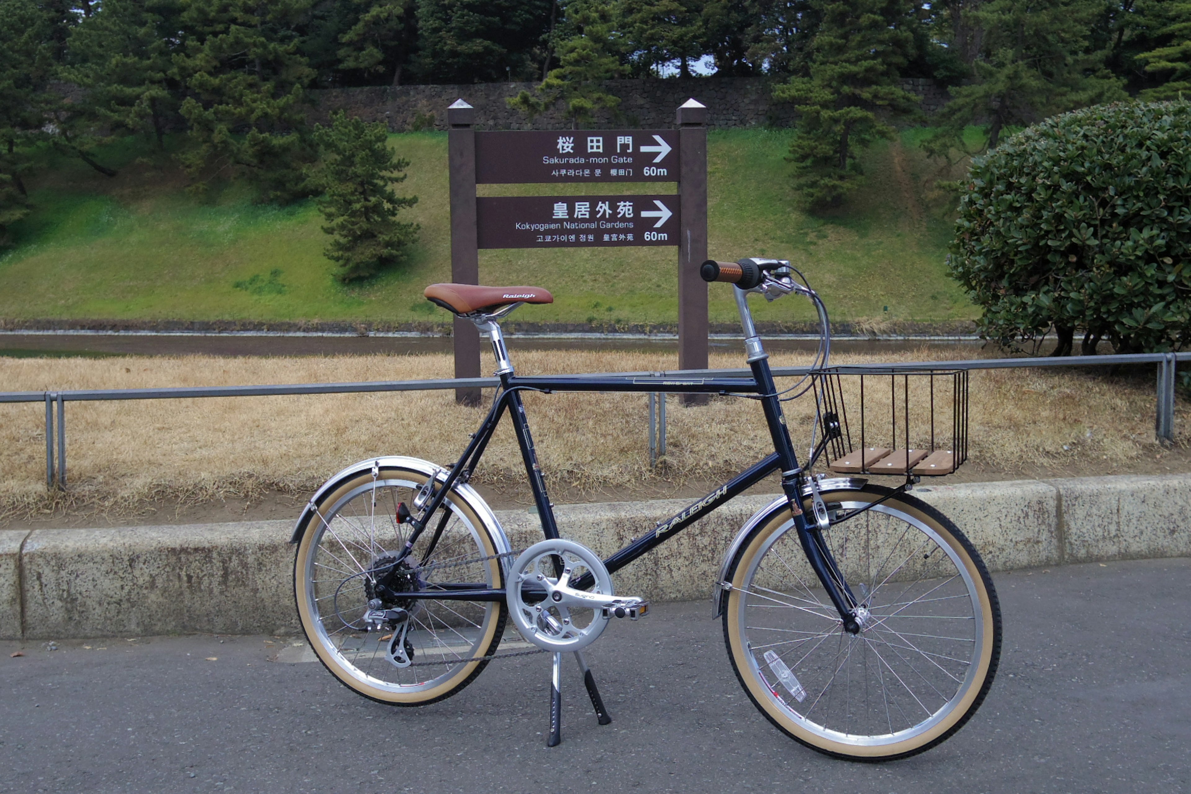 A bicycle parked in front of a park sign with directional arrows