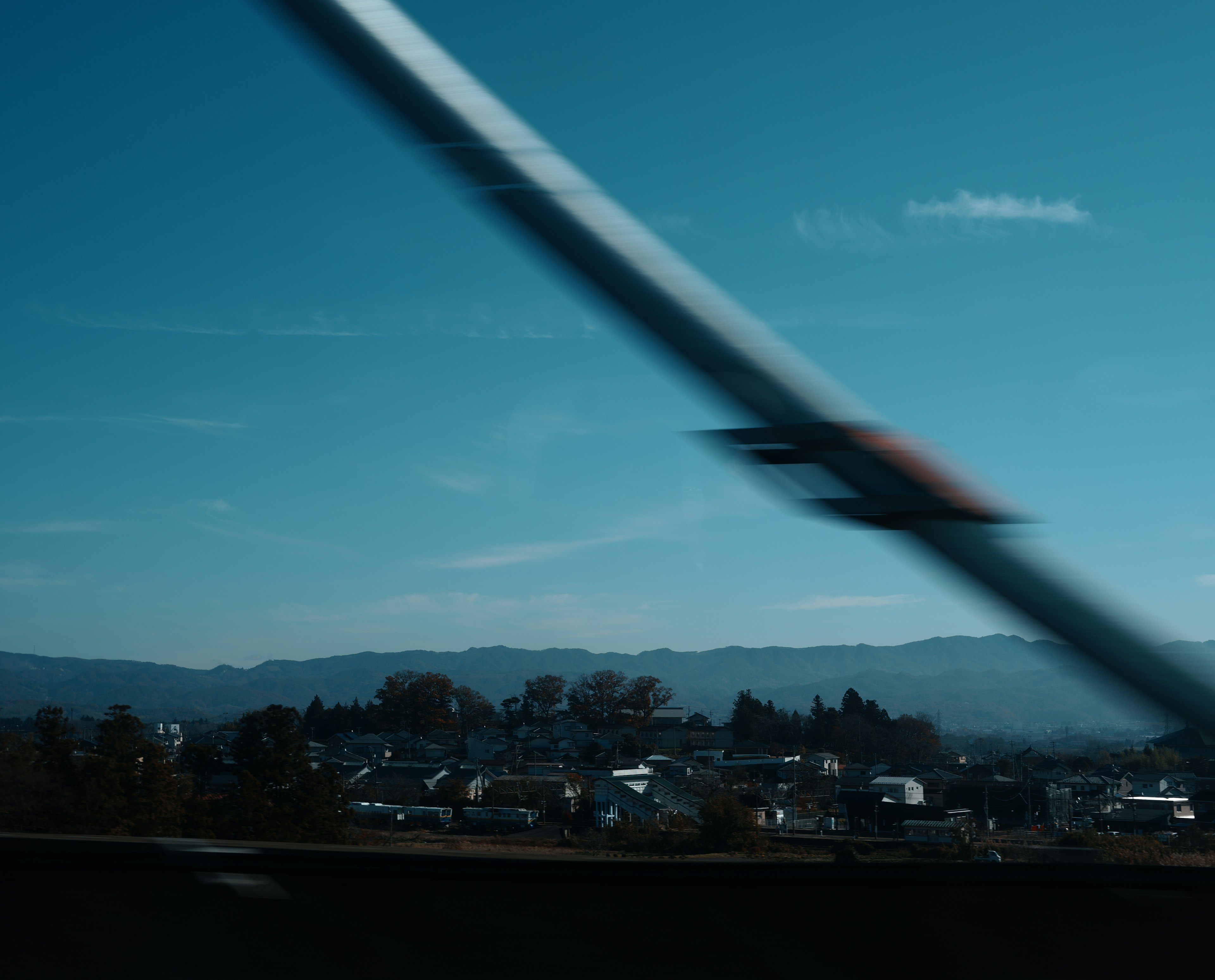 City landscape under a blue sky with motion blur from a passing vehicle