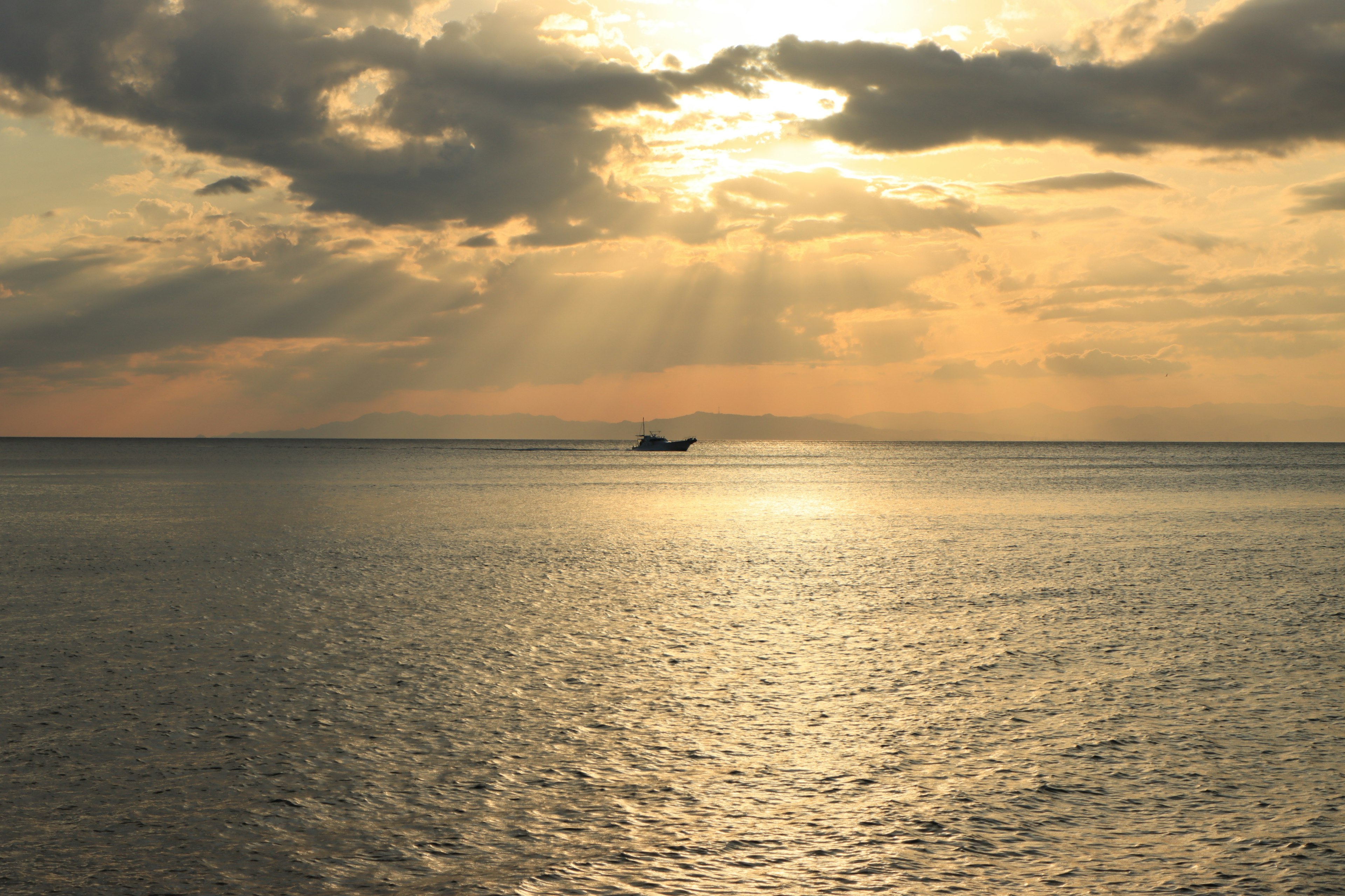 Eine ruhige Meereslandschaft bei Sonnenuntergang mit einem kleinen Boot in Silhouette