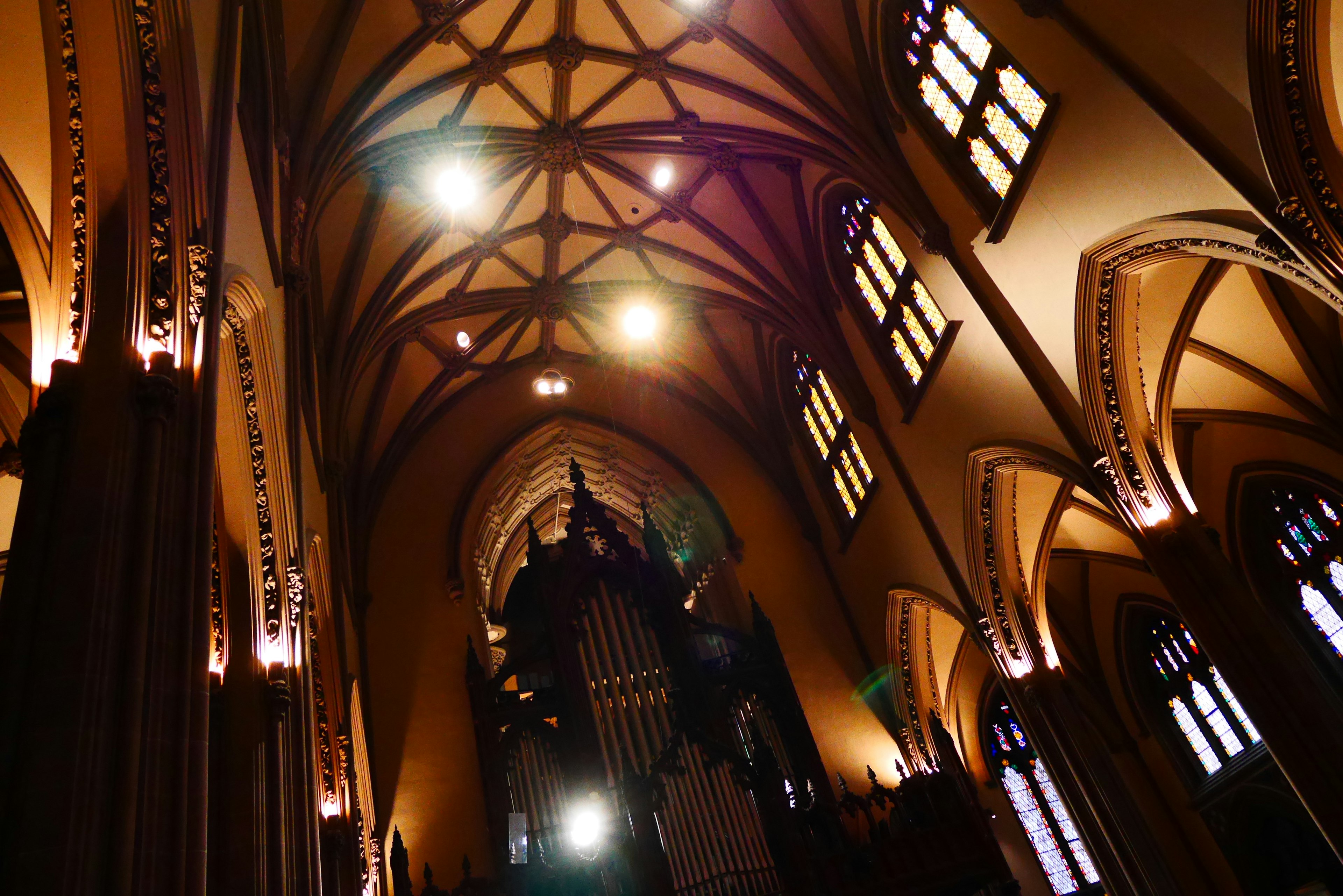 Vue intérieure d'une église gothique avec un plafond complexe et des vitraux