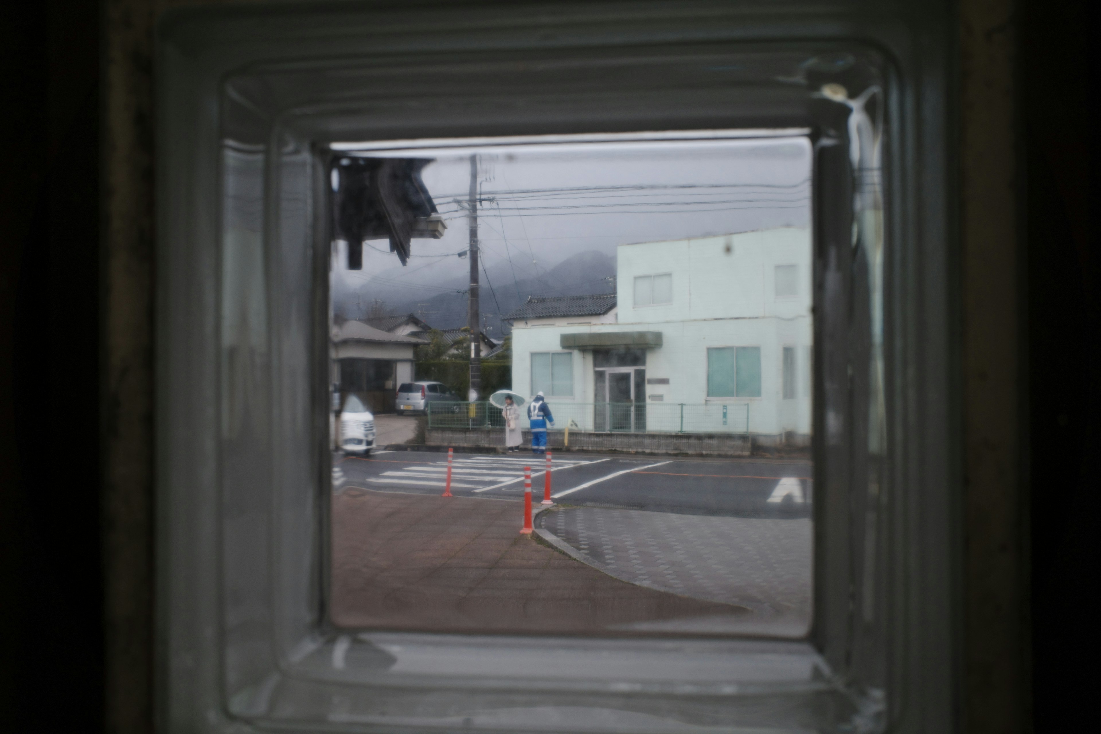 Vue de la rue à travers une fenêtre en verre avec un bâtiment blanc et des nuages sombres