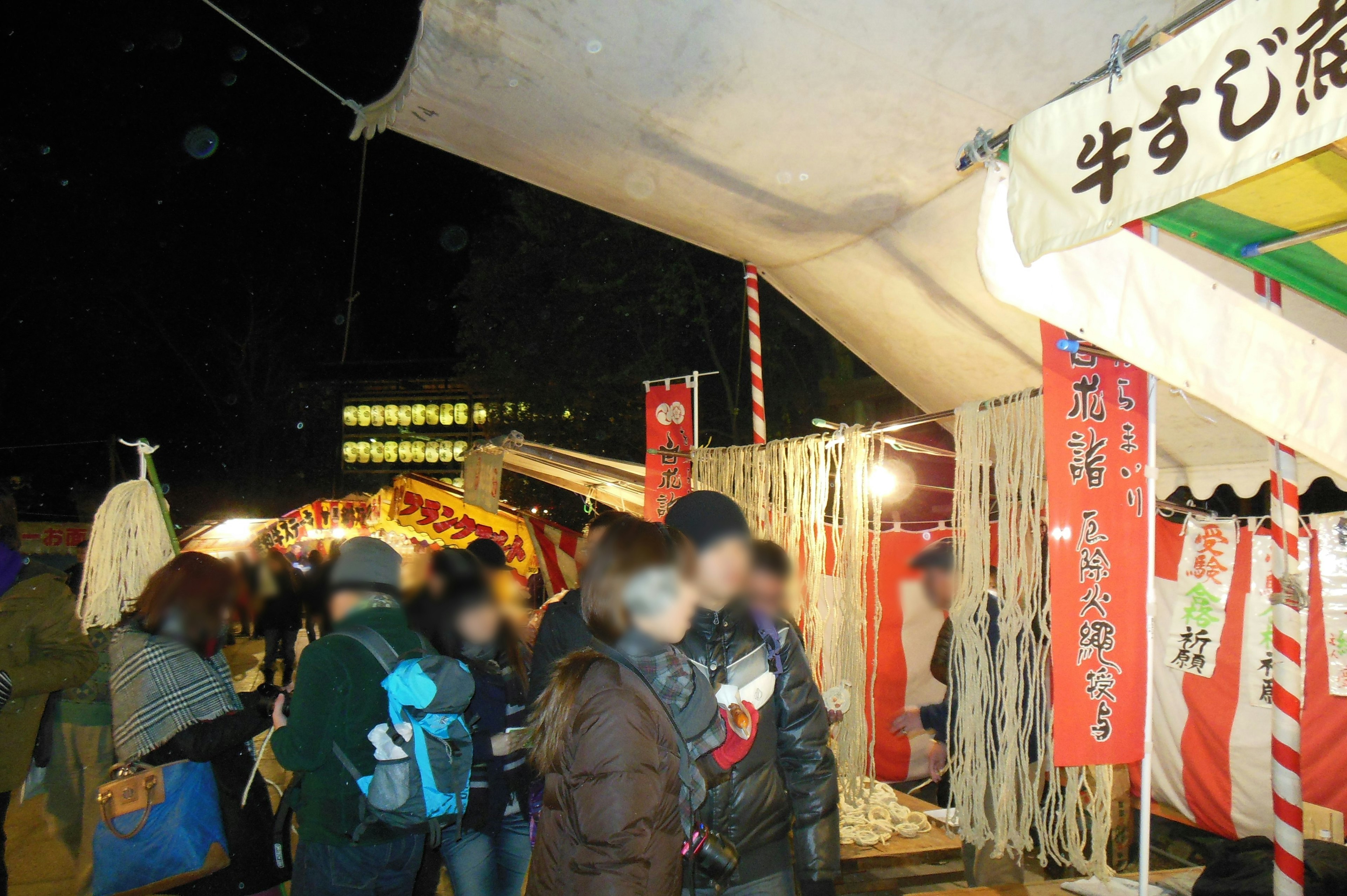 Menschenmenge auf einem Nachtmarkt mit bunten Ständen und Laternen