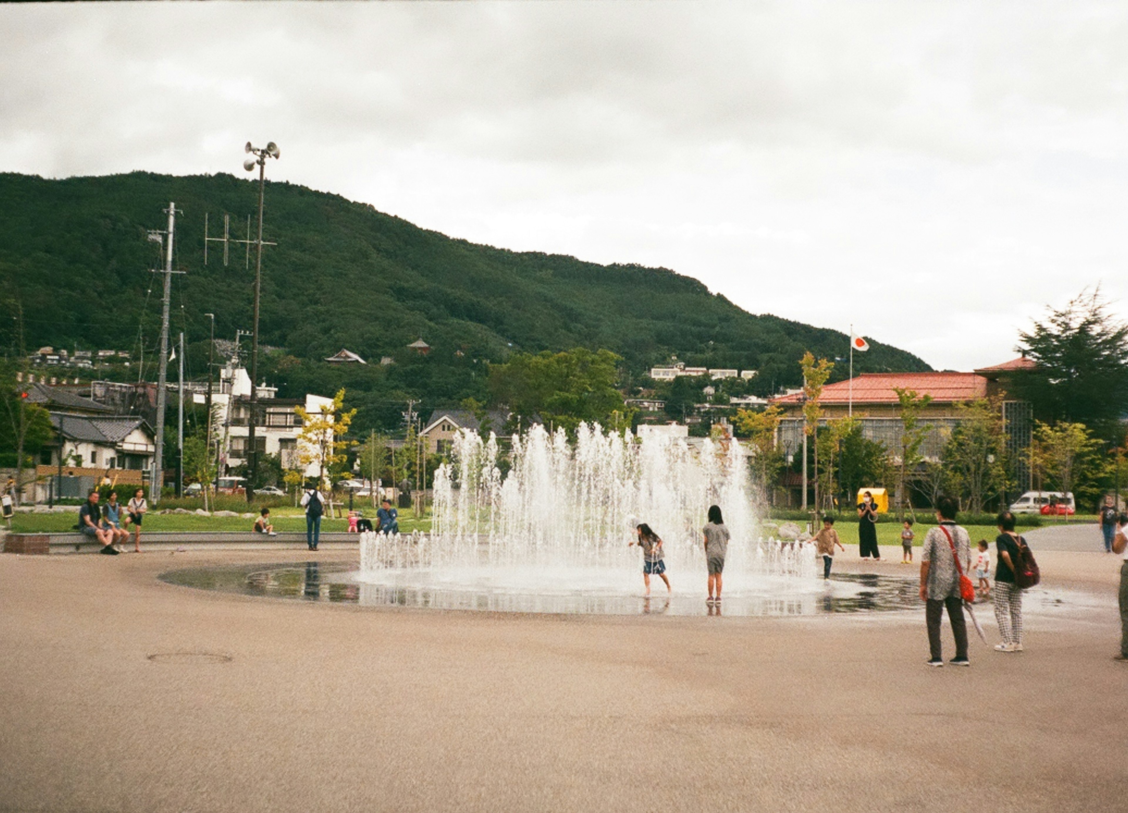 公園の噴水で遊ぶ子供たちと大人たちの風景