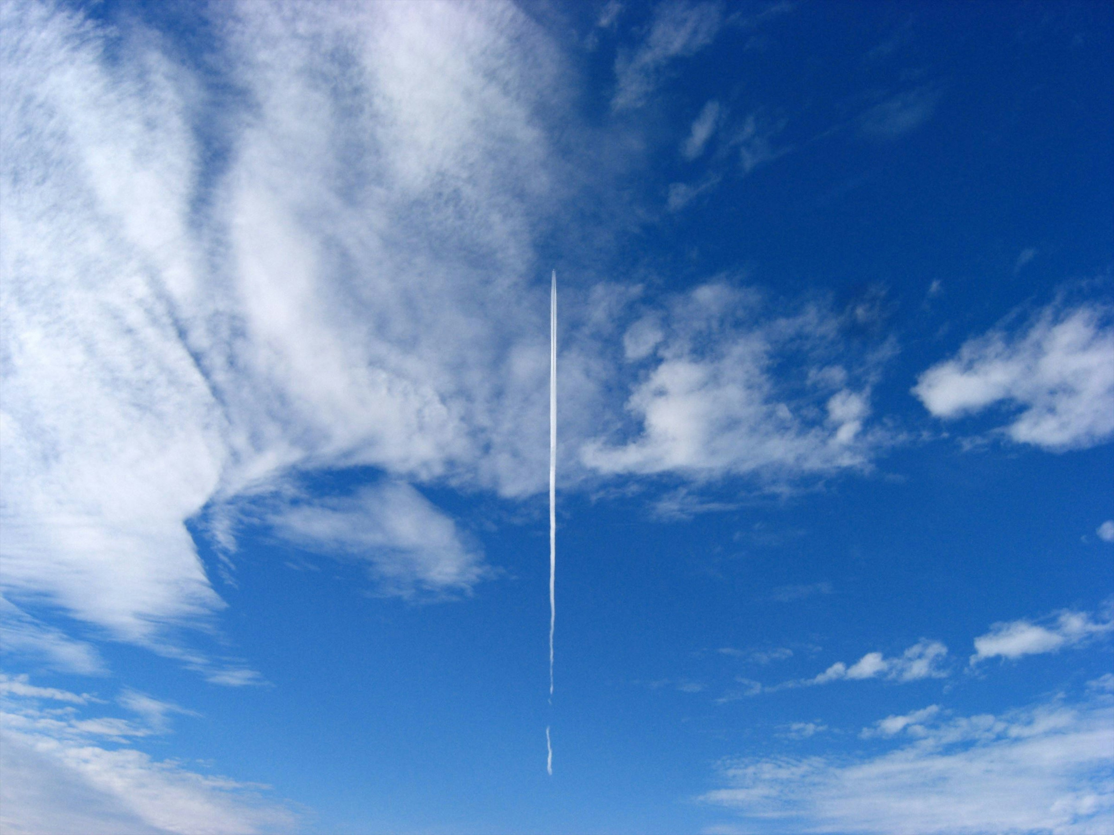 Une traînée d'avion longue s'étend à travers un ciel bleu clair