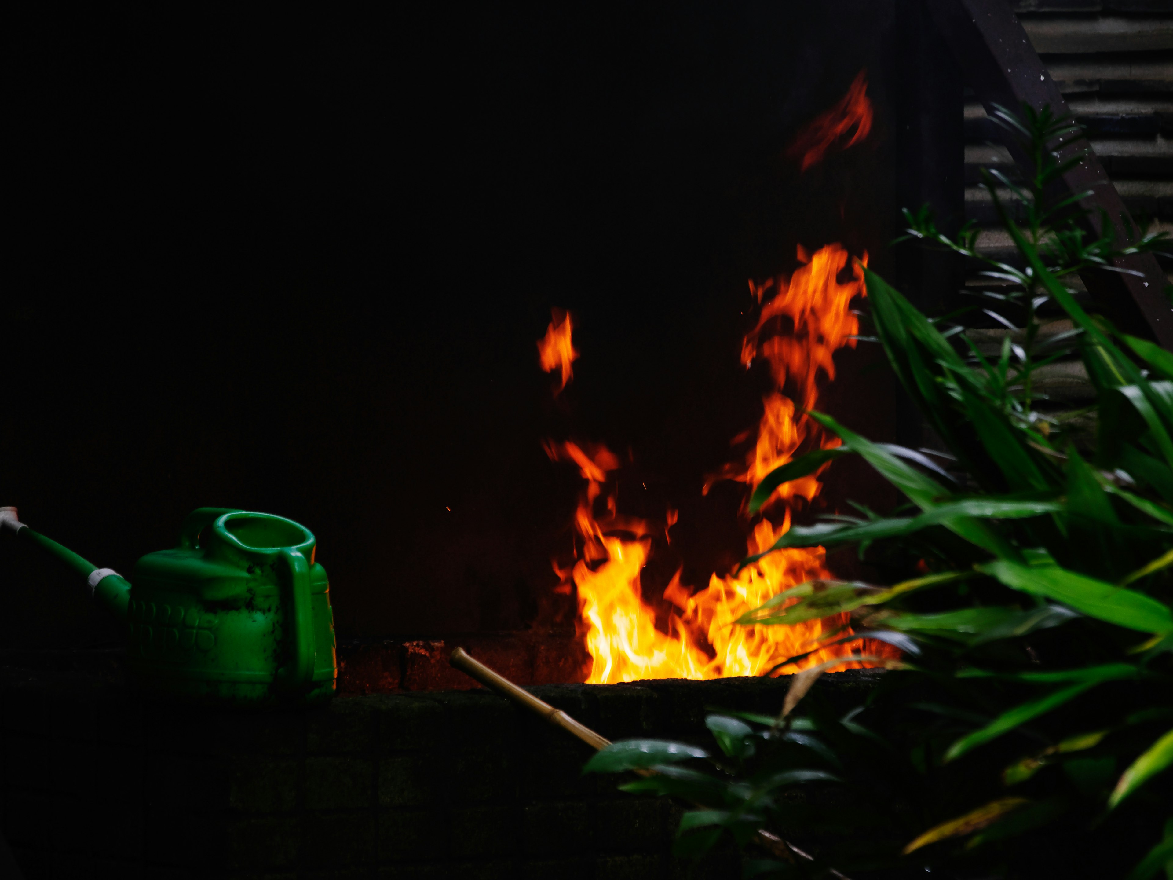 Flames burning in a dark background with a green watering can