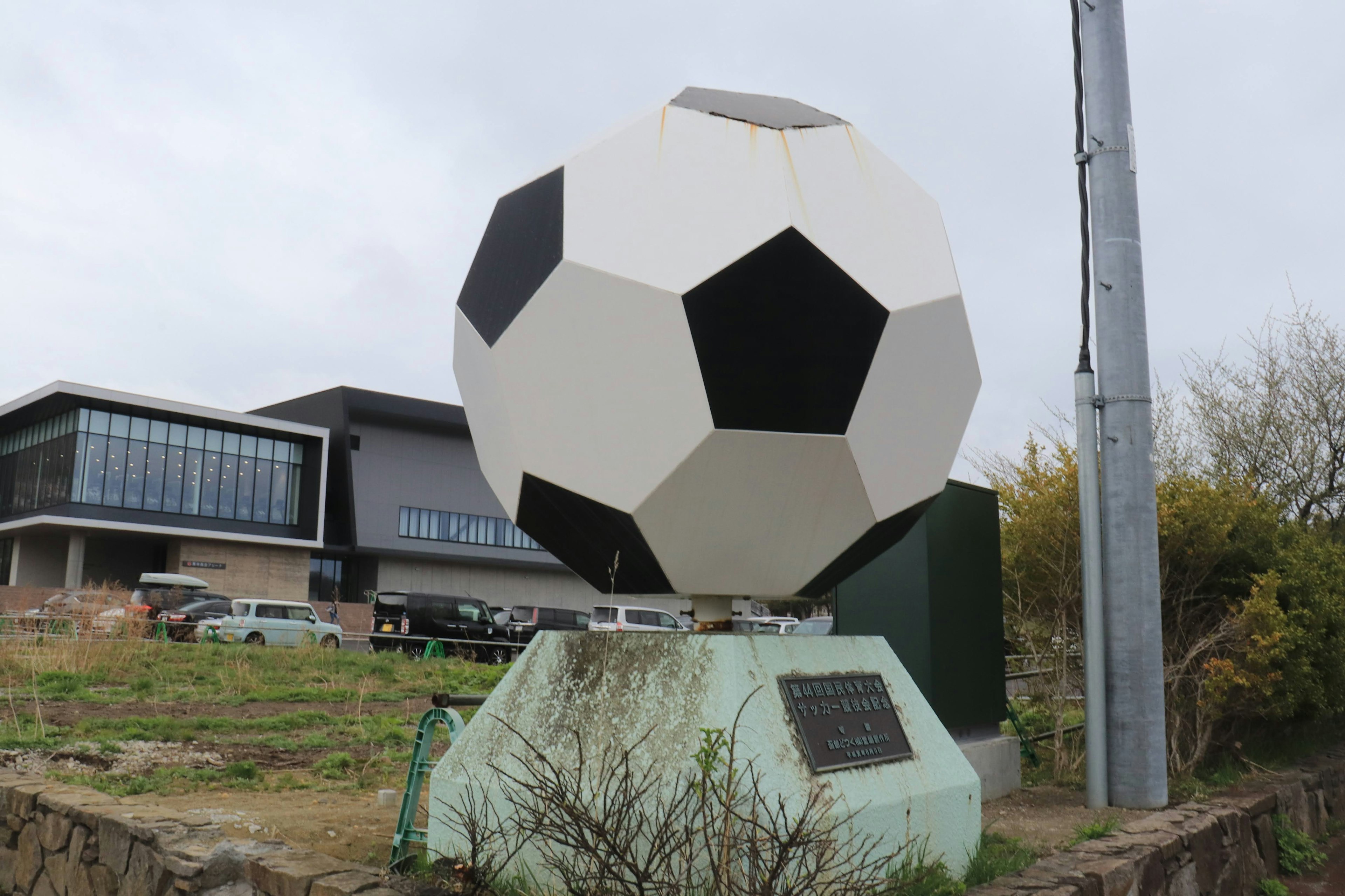 Patung bola sepak raksasa di lanskap dengan gedung modern