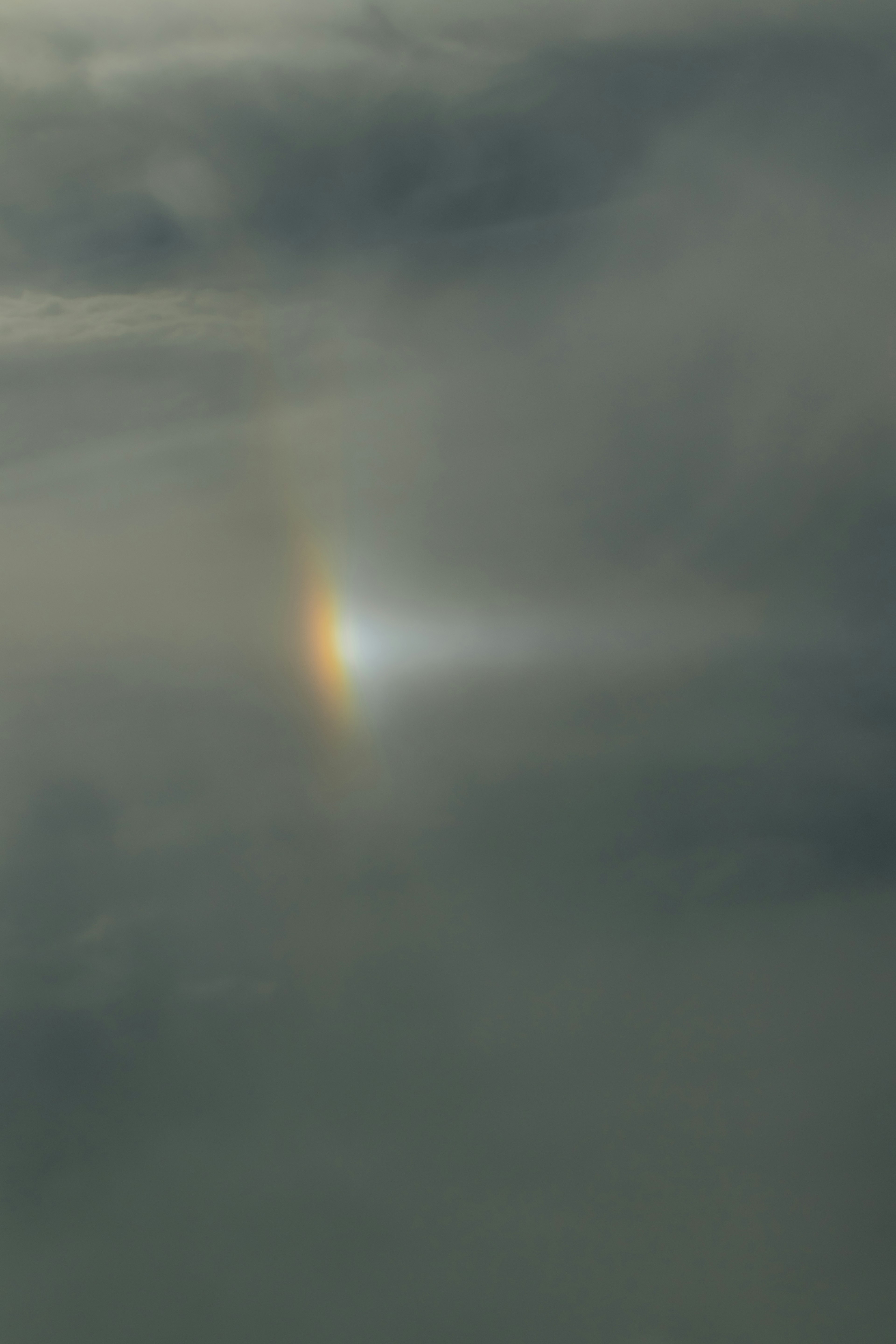 Una franja de luz arcoíris apareciendo en un cielo nublado