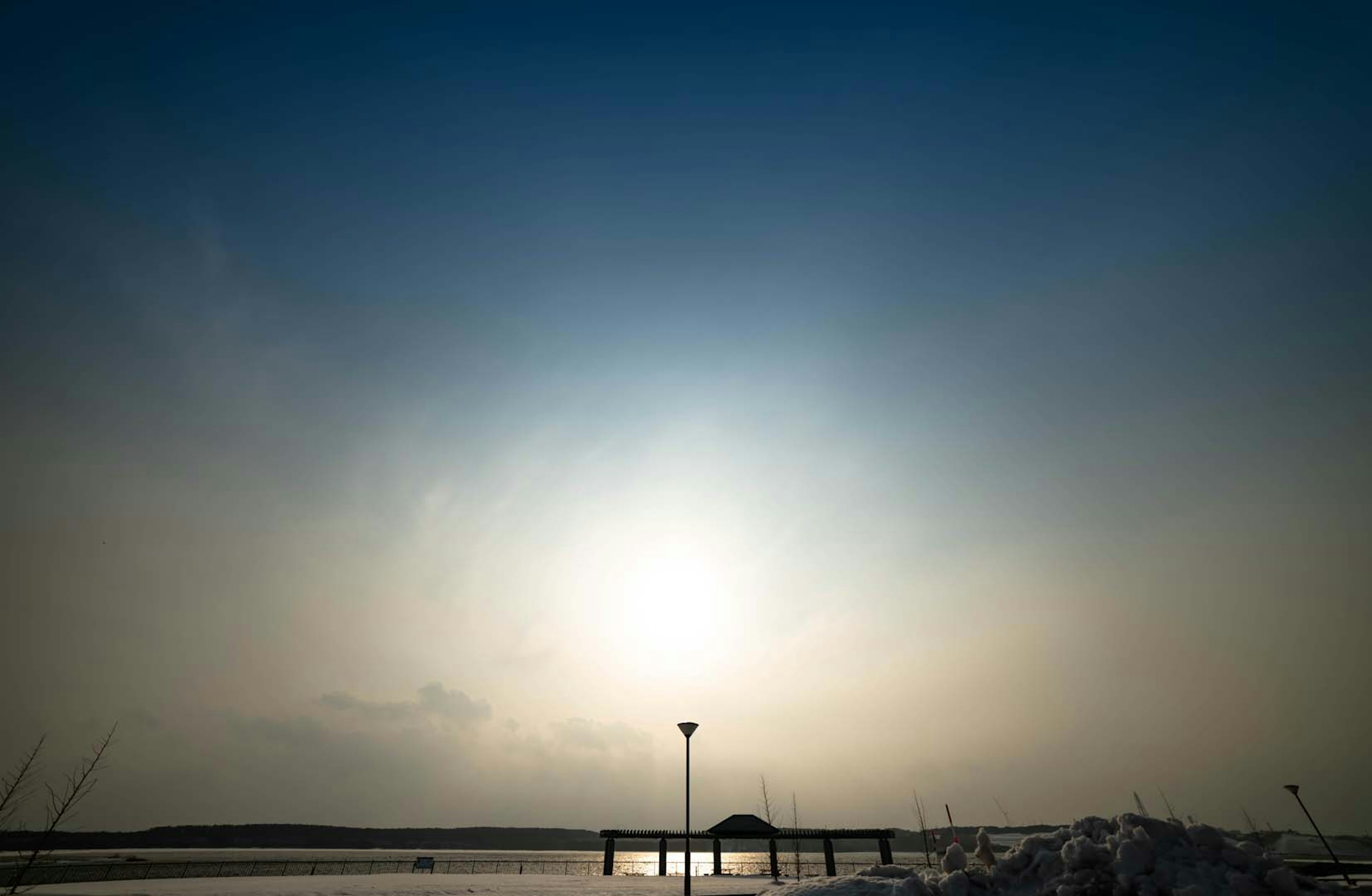 Serene lake view with a pier and a light during a beautiful sunset