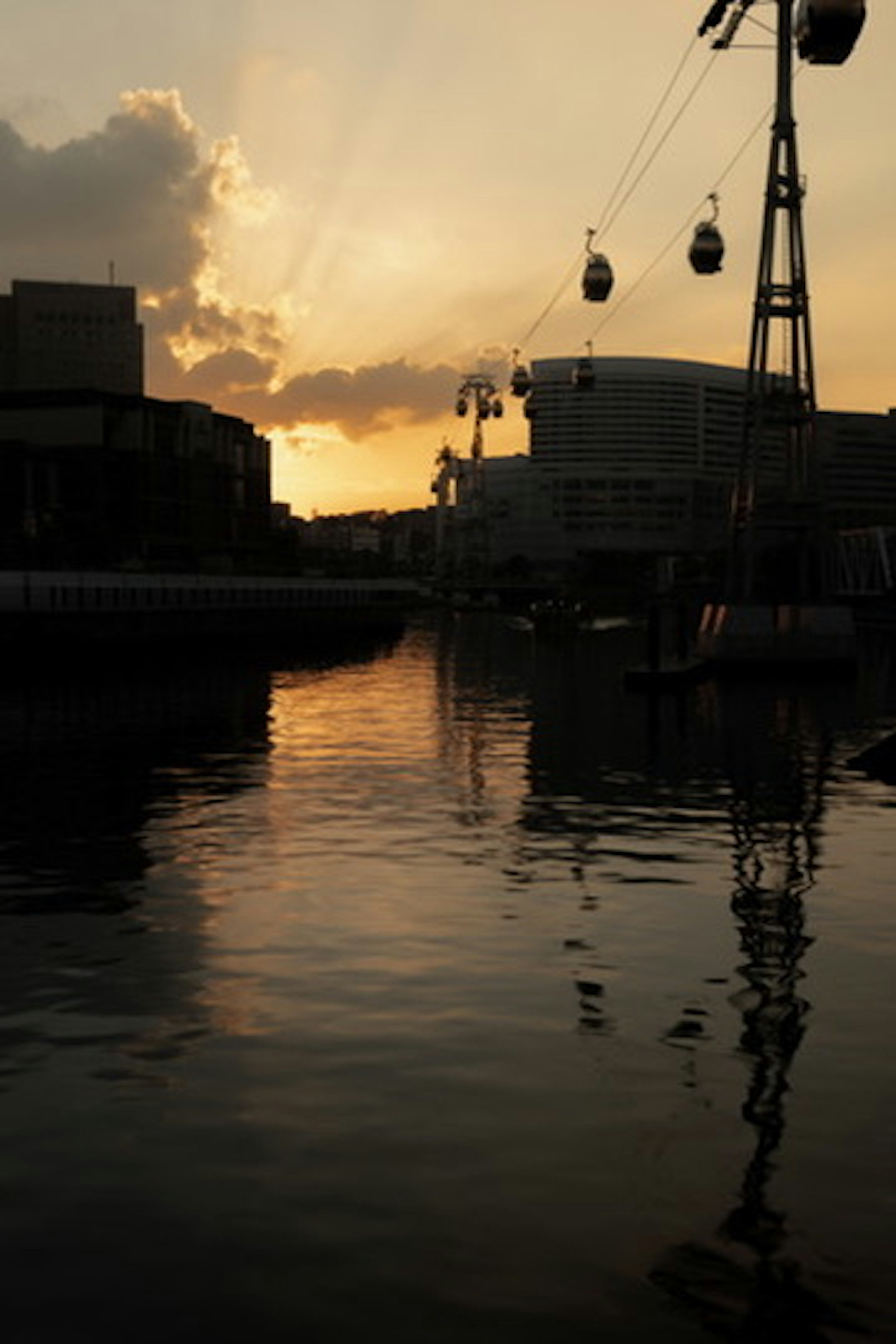 Silhouette di un tramonto che si riflette sull'acqua con funivie