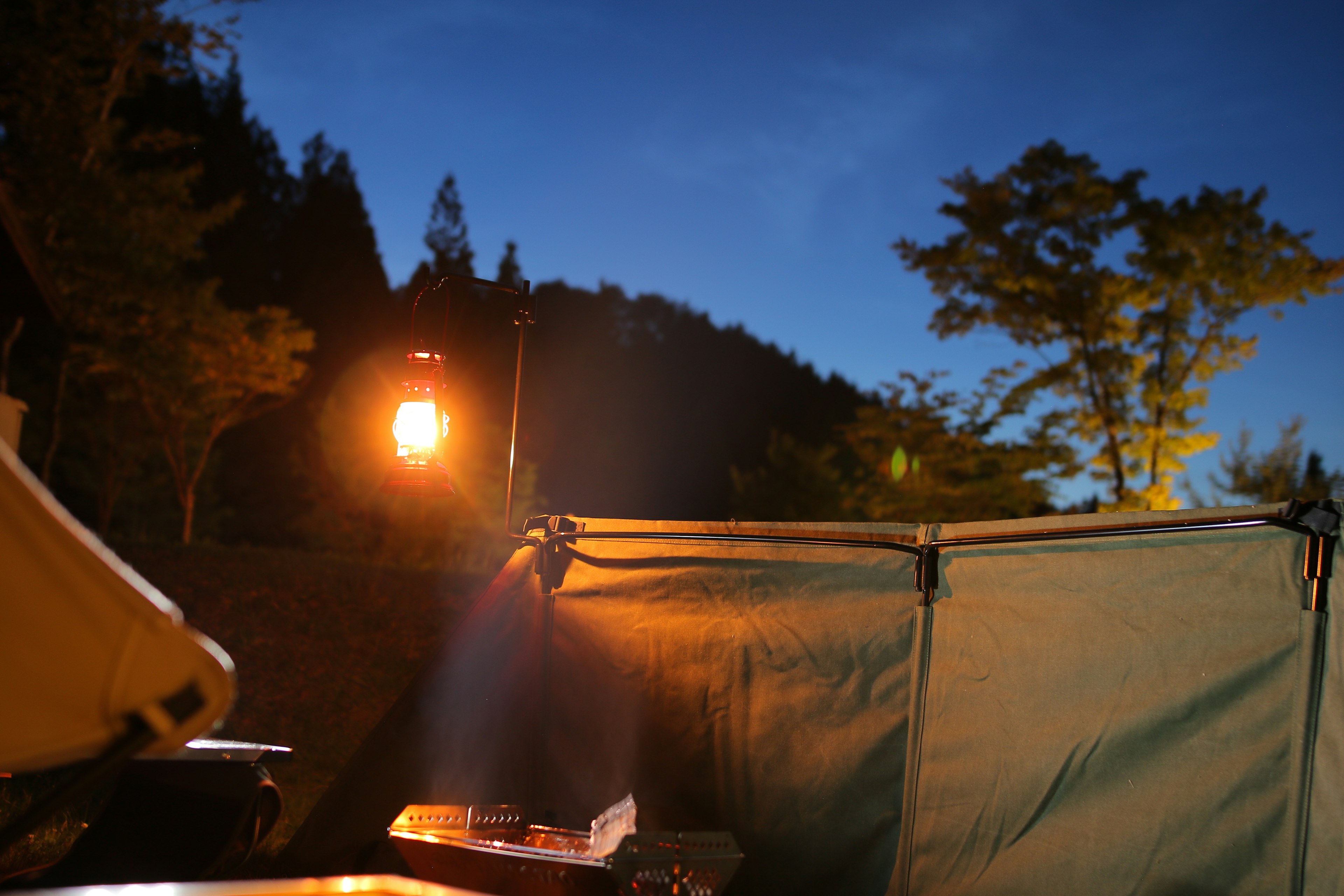 Night view of a campsite featuring a tent and lamp