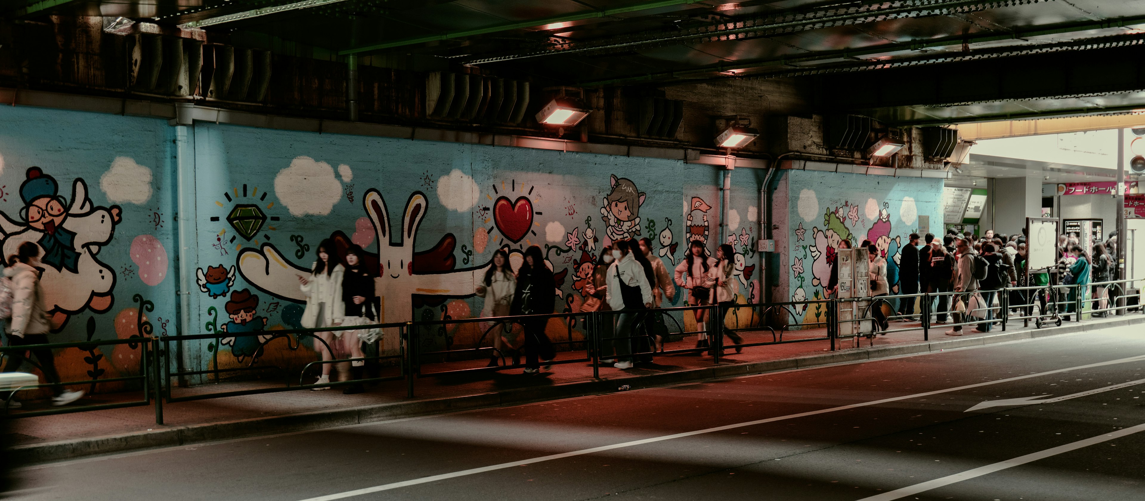 People standing in front of a colorful mural in an underpass