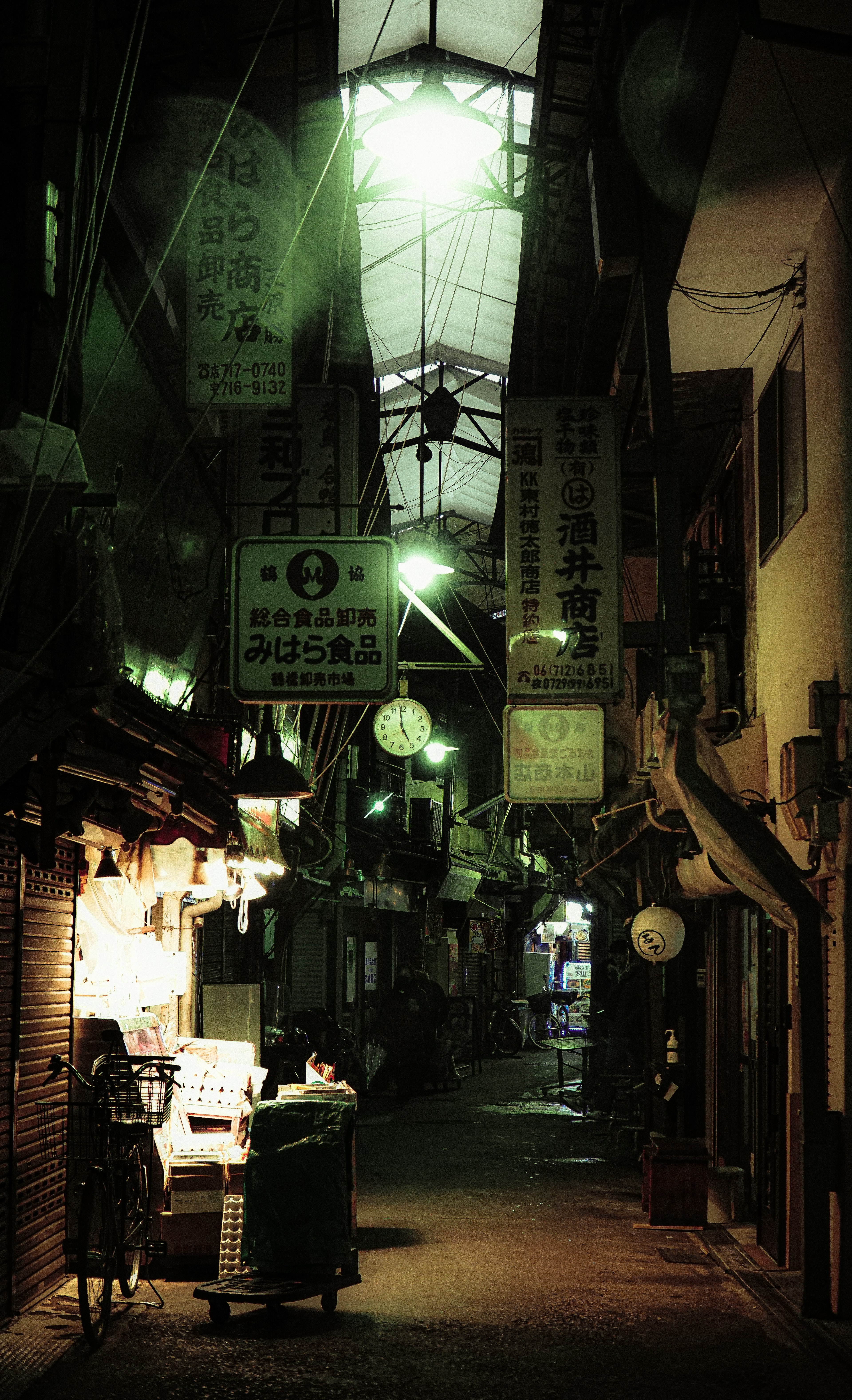 薄暗い路地に並ぶ看板と提灯のある景色