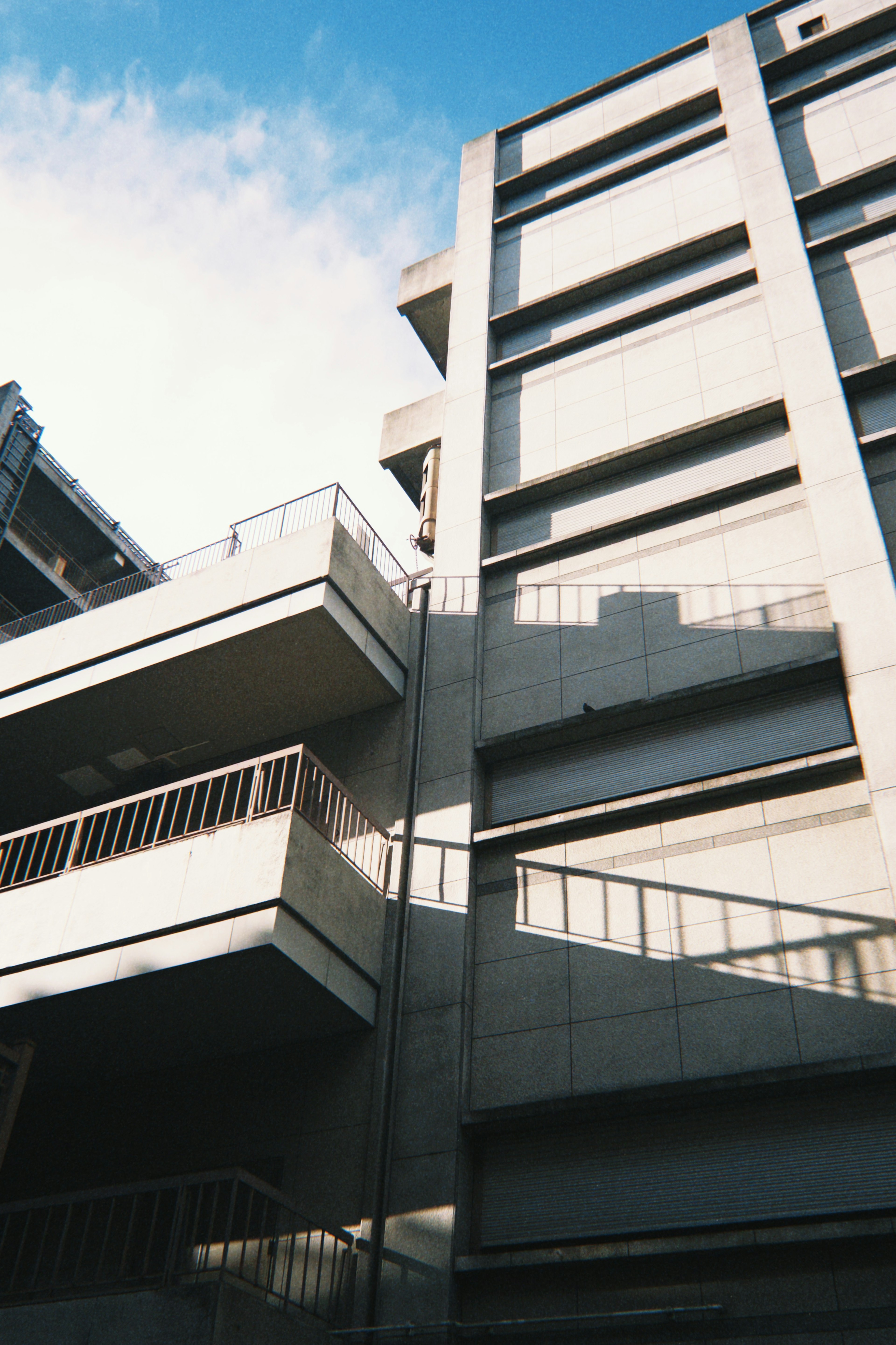 Exterior de un edificio de concreto con balcones visibles y sombras