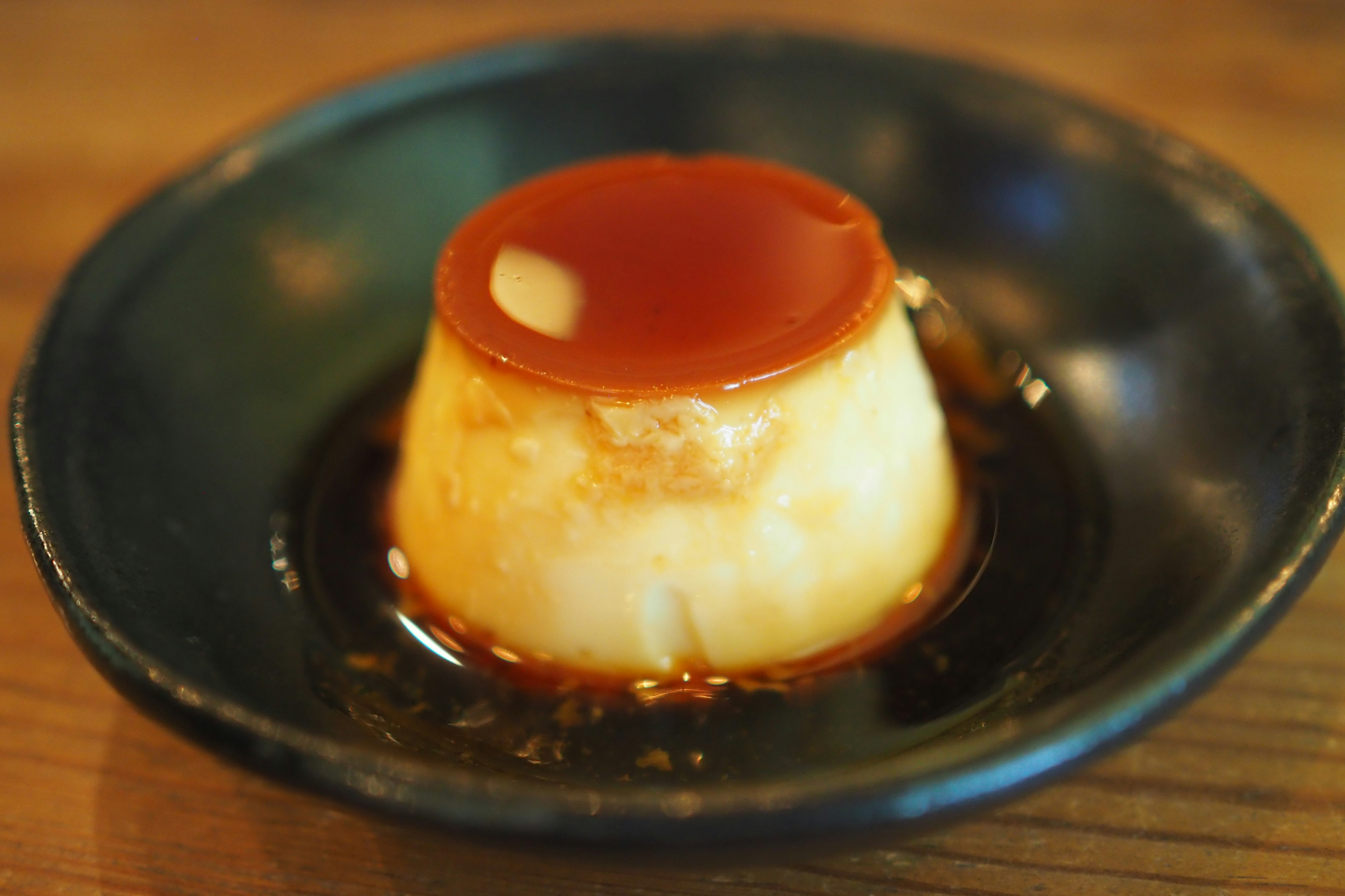 Postre flan cubierto con salsa de caramelo en un plato negro