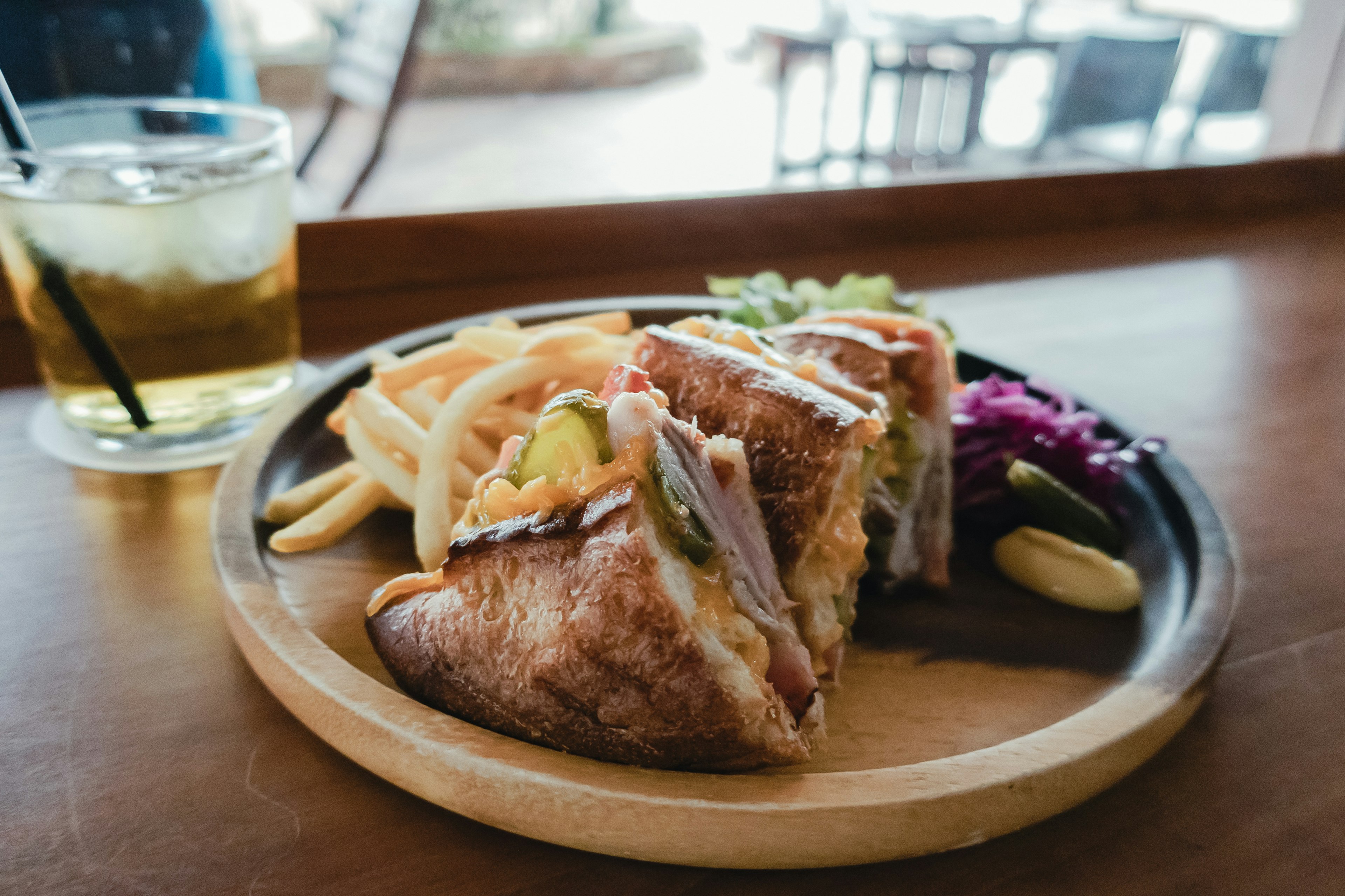 Piring kayu dengan sandwich dan kentang goreng serta minuman