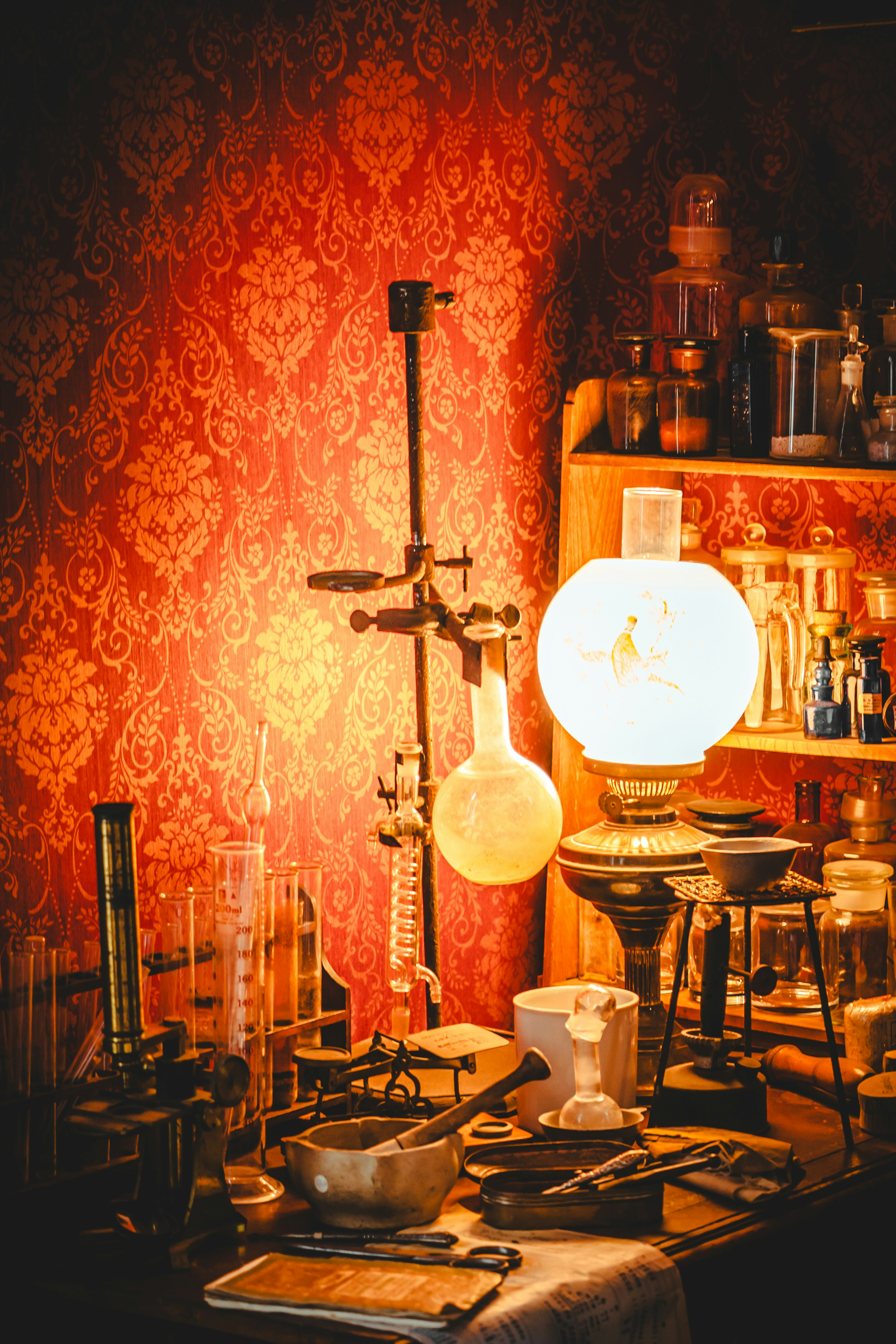 Une collection d'équipements scientifiques vintage et d'une lampe sur fond de papier peint rouge