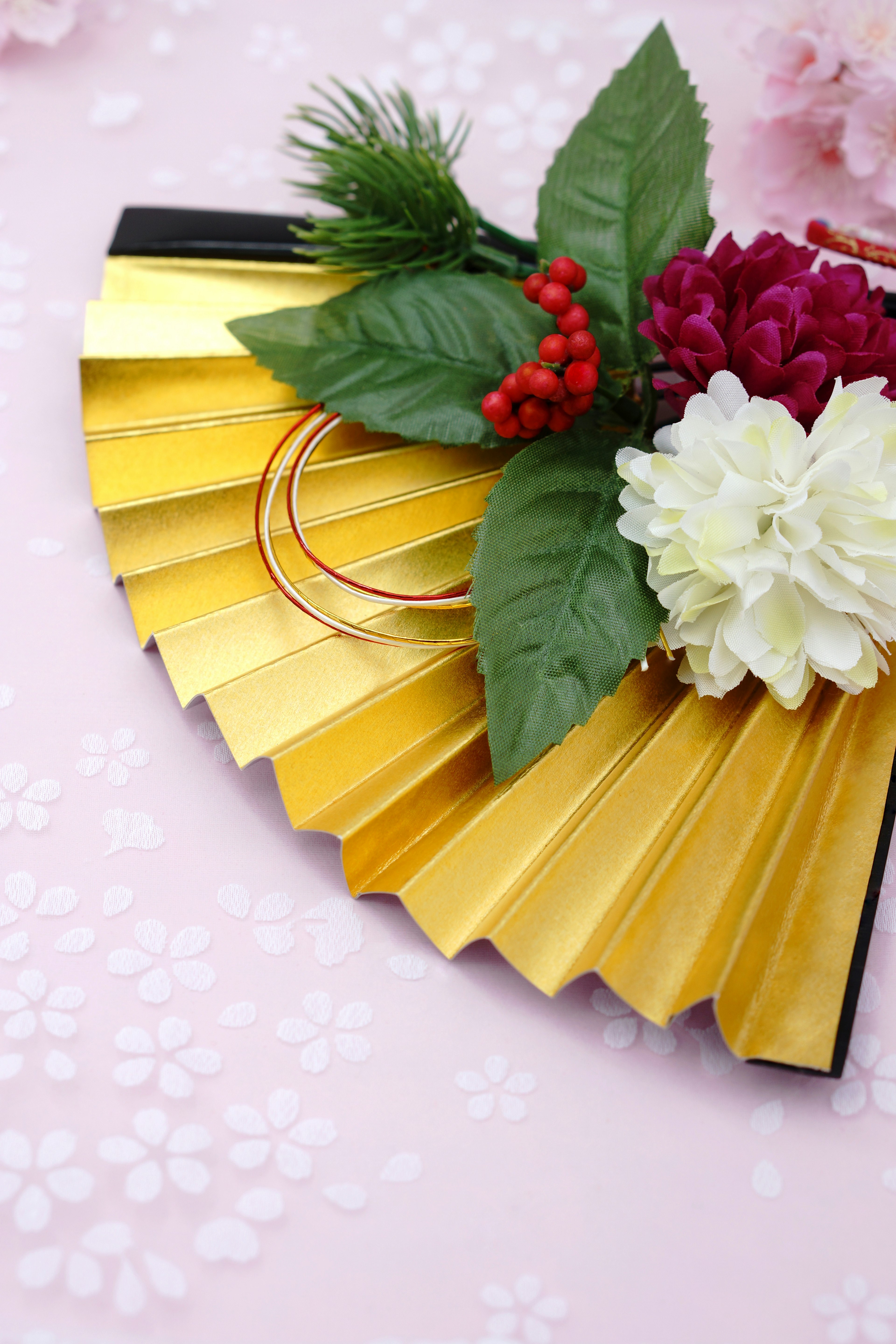 A decorative golden fan adorned with flowers and leaves