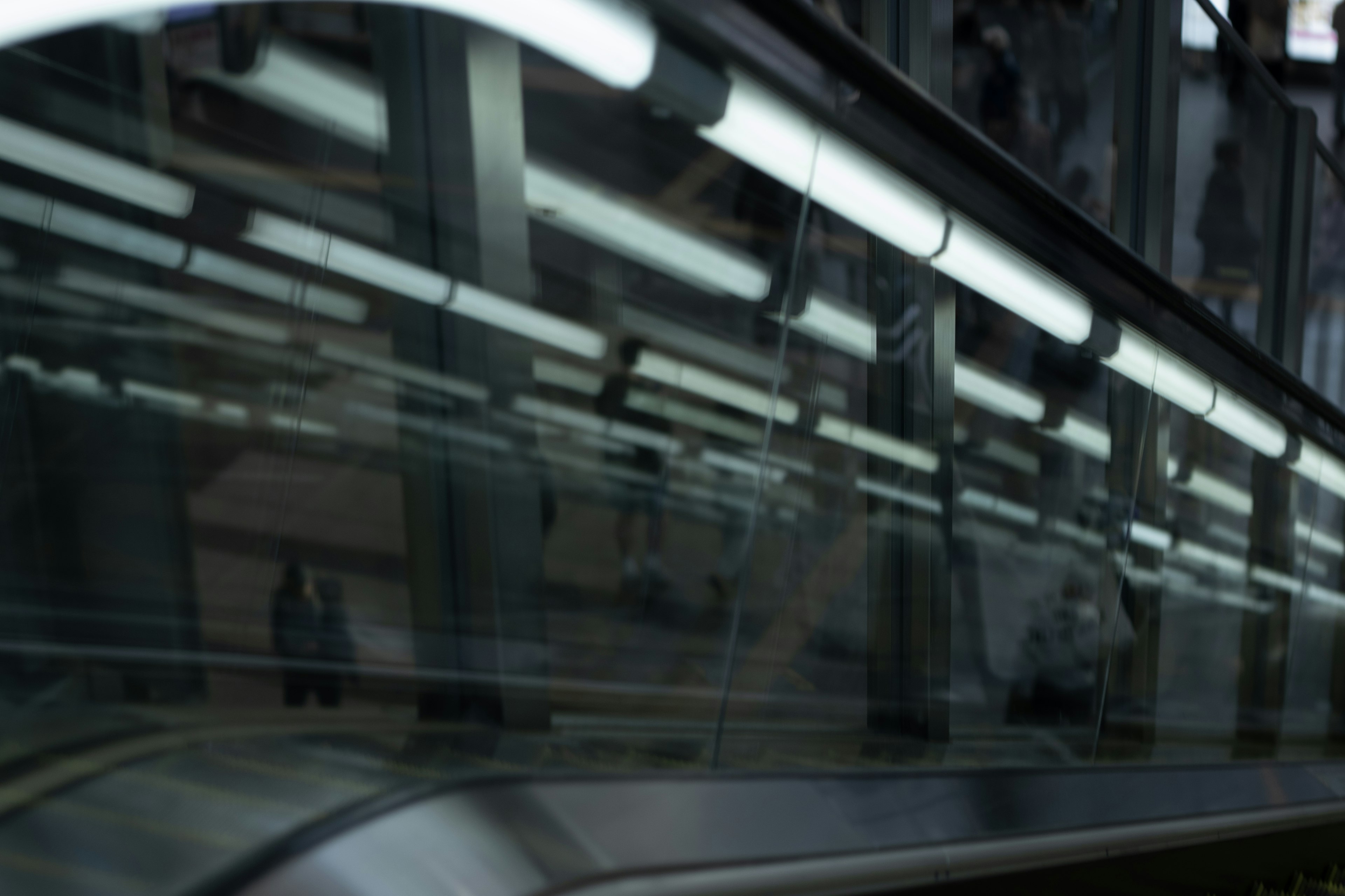 Escena urbana capturada cerca de una escalera mecánica con reflejos de luces superiores