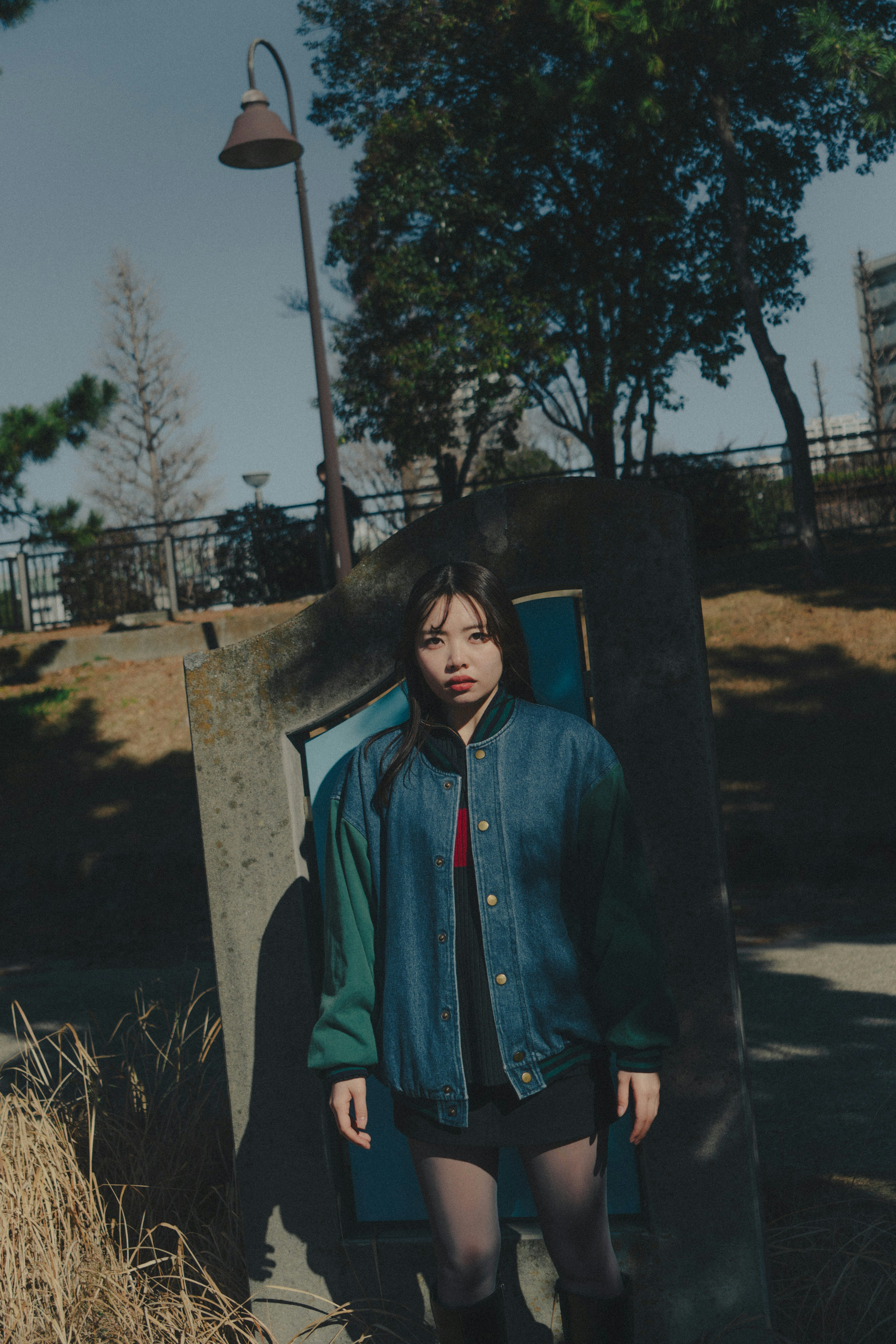 A woman standing in a park wearing a blue jacket