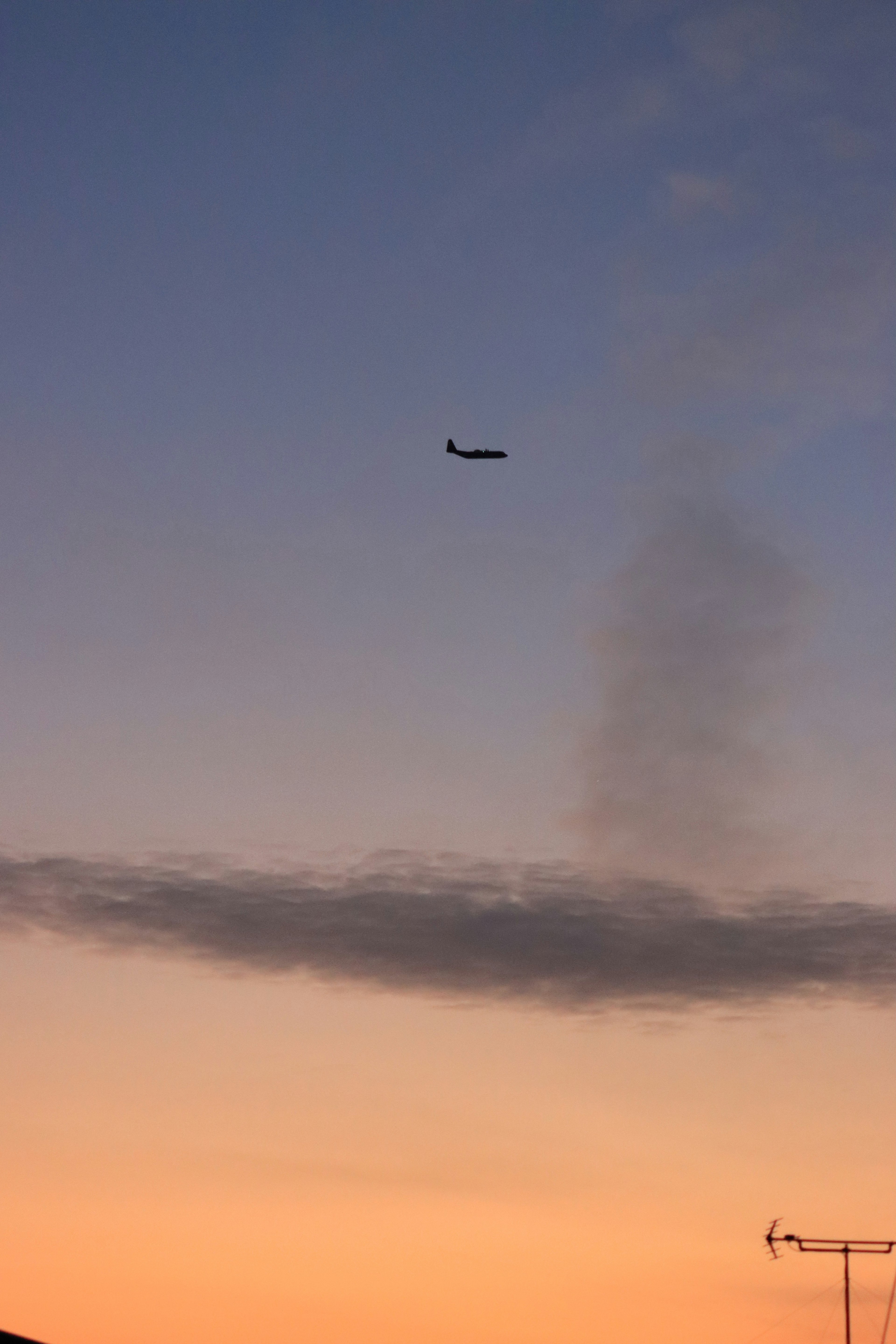 夕焼けの空に飛行機が飛ぶ様子