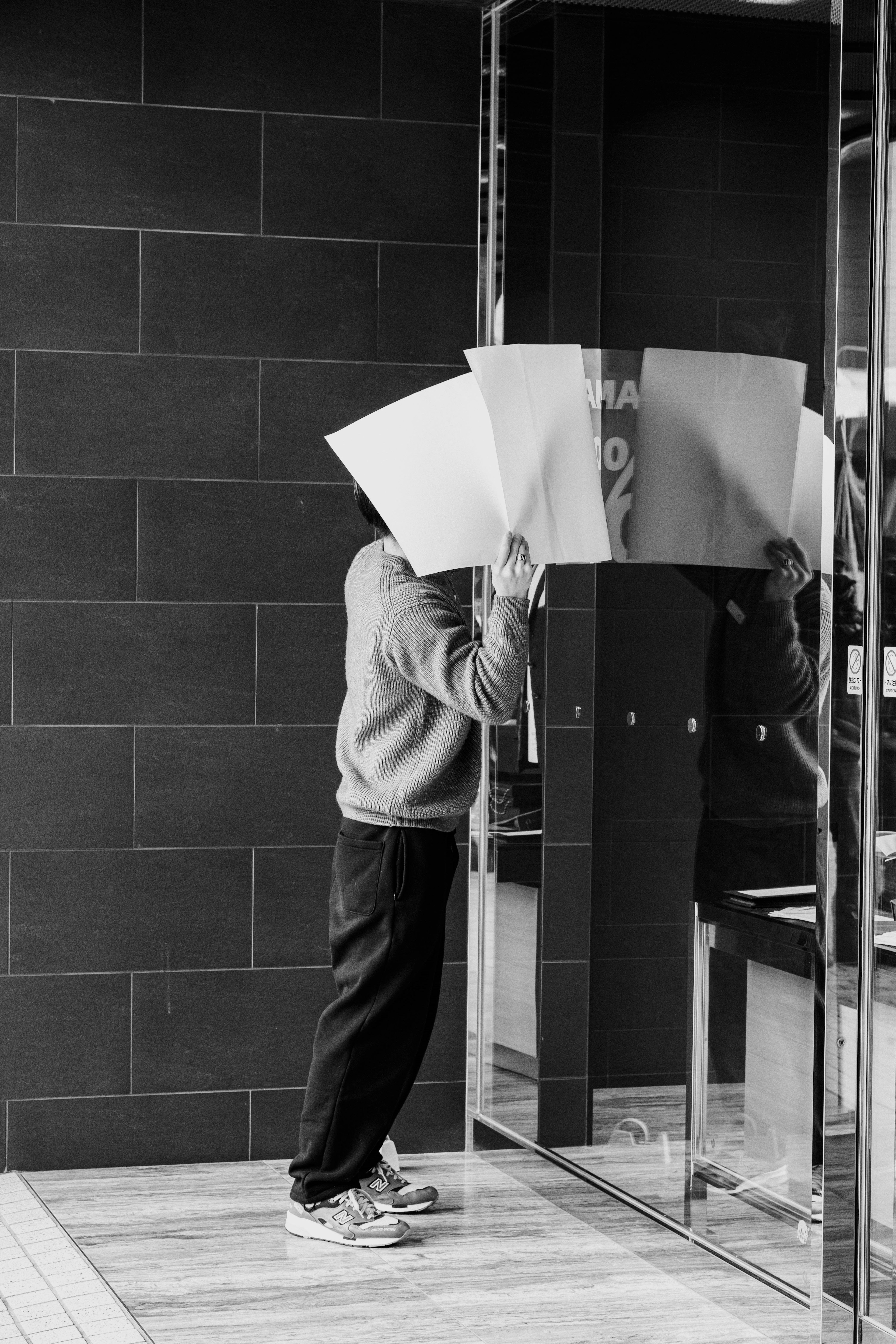 Person standing against a black and white background holding large white papers