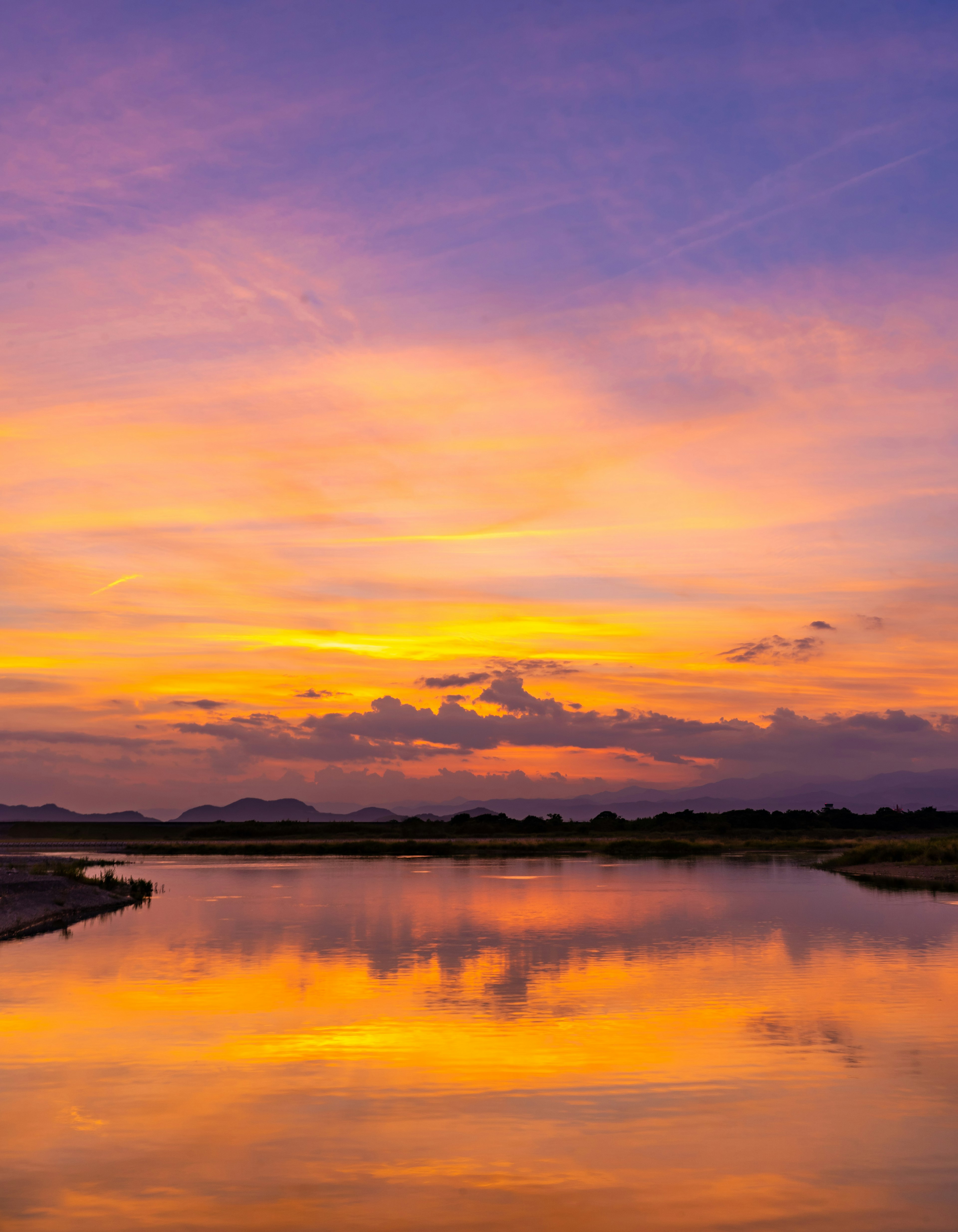 Pemandangan sungai yang indah saat matahari terbenam dengan refleksi langit berwarna di atas air