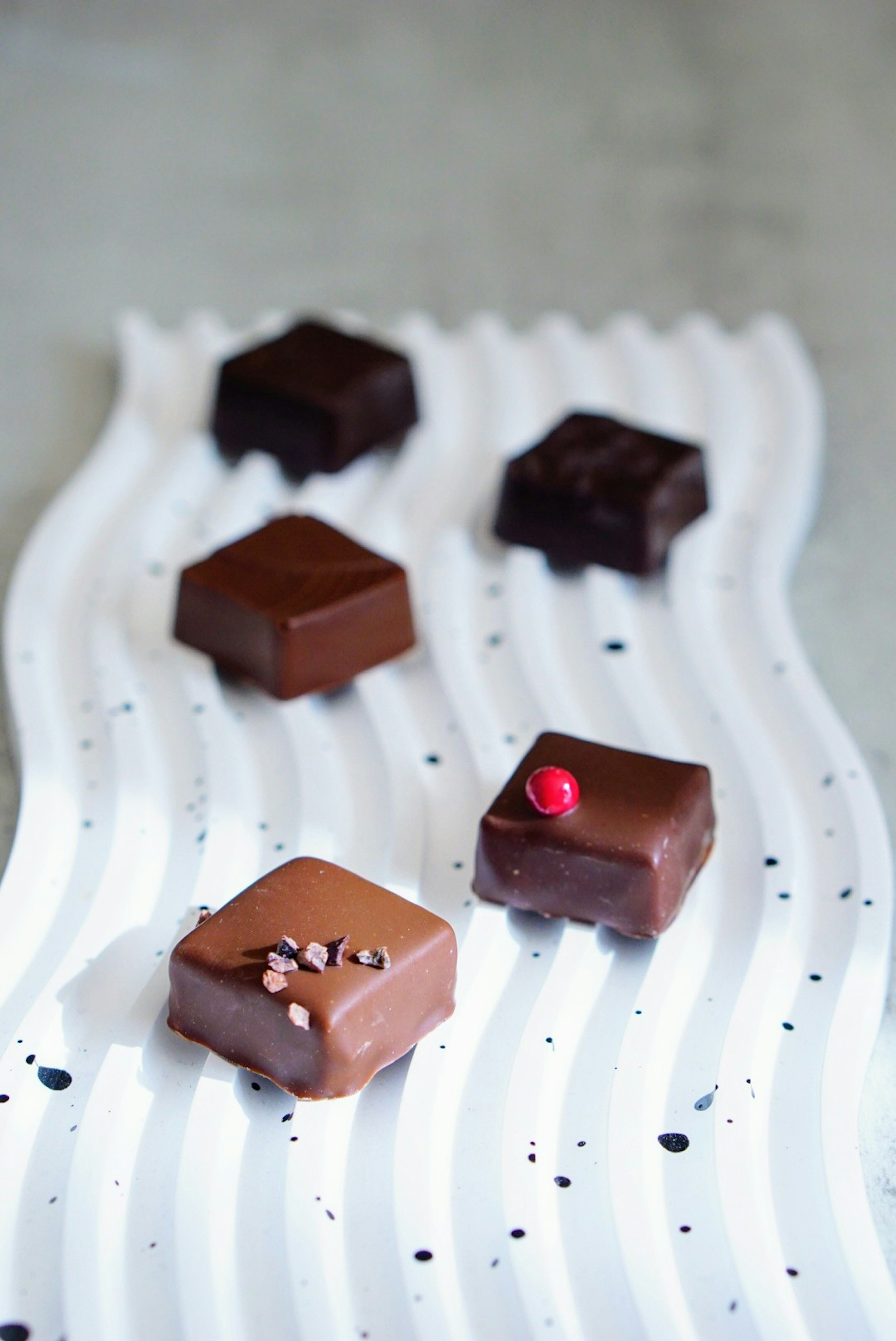 Assorted chocolate bonbons arranged on a wavy white plate