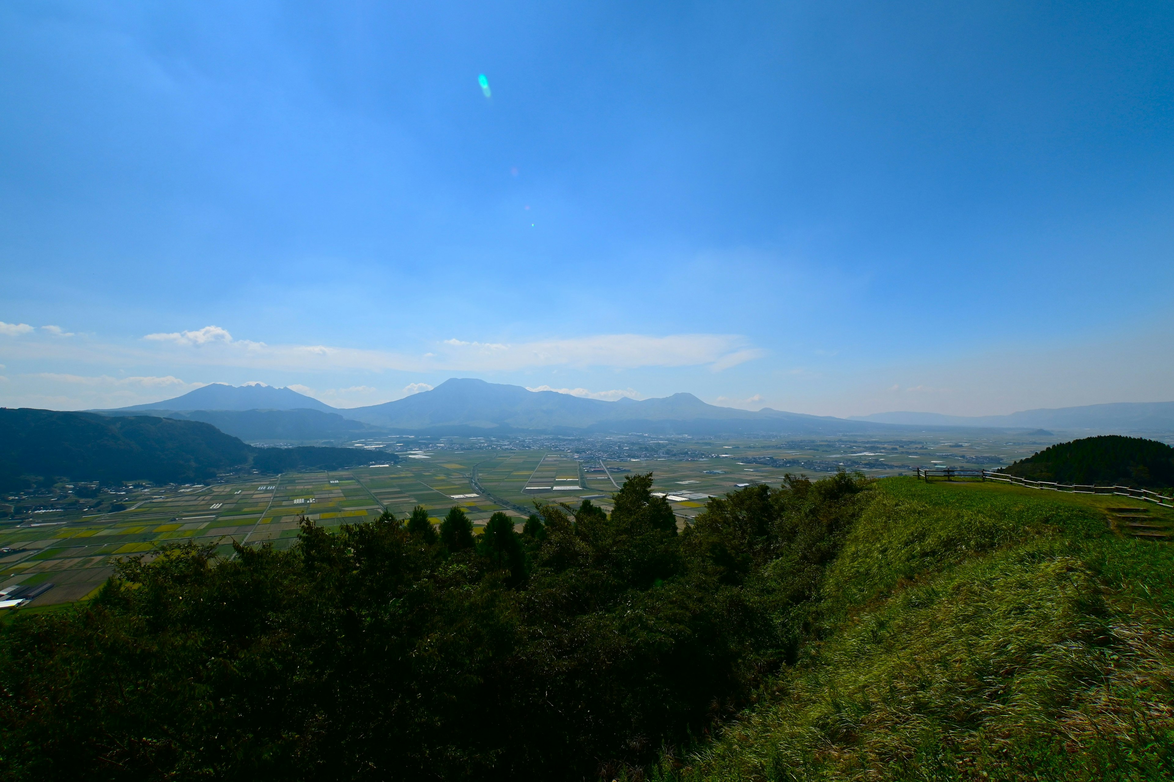 青空に広がる山々と緑豊かな丘の風景