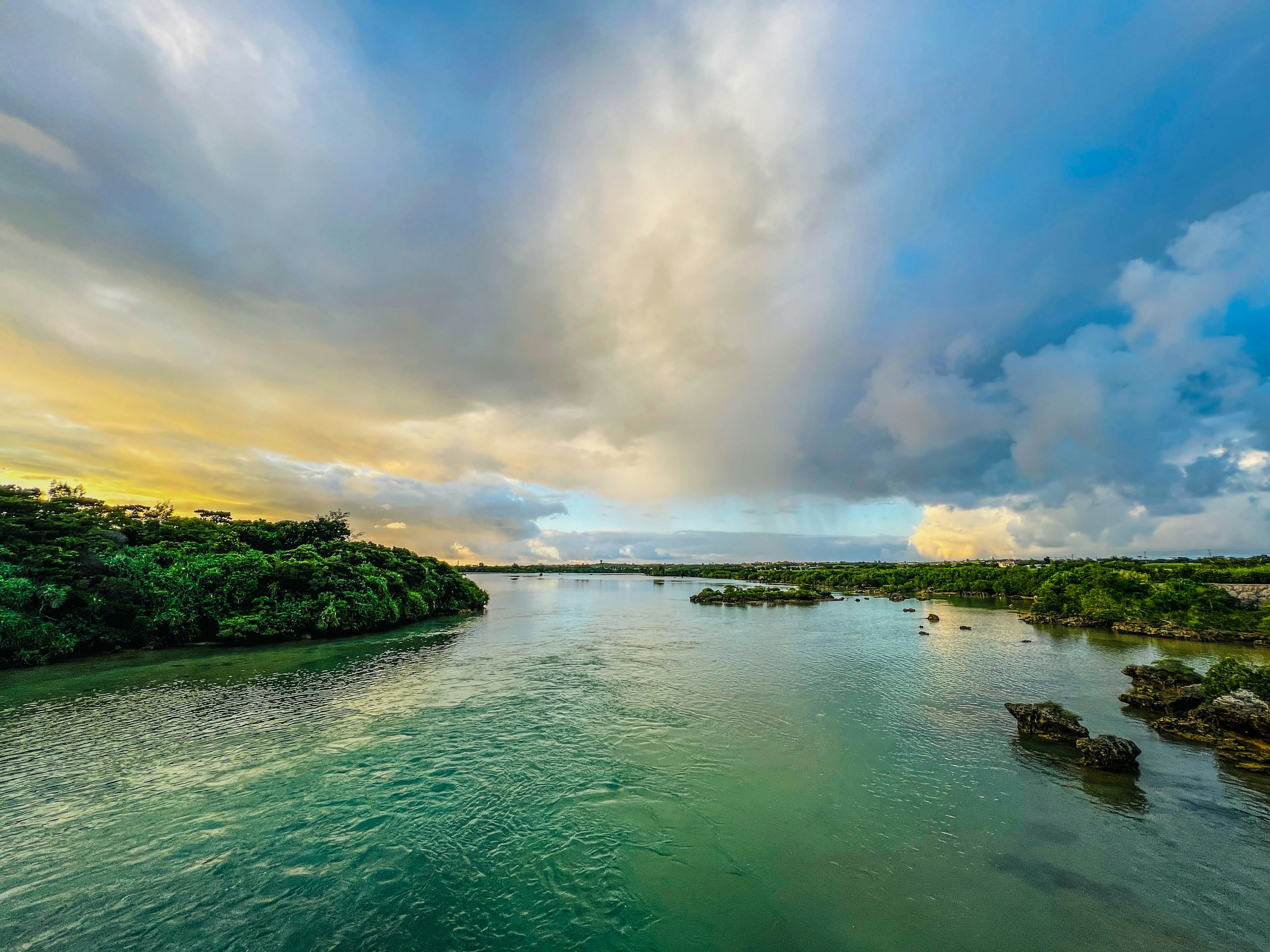 Pemandangan sungai dengan langit biru dan awan tepi hijau dan air tenang