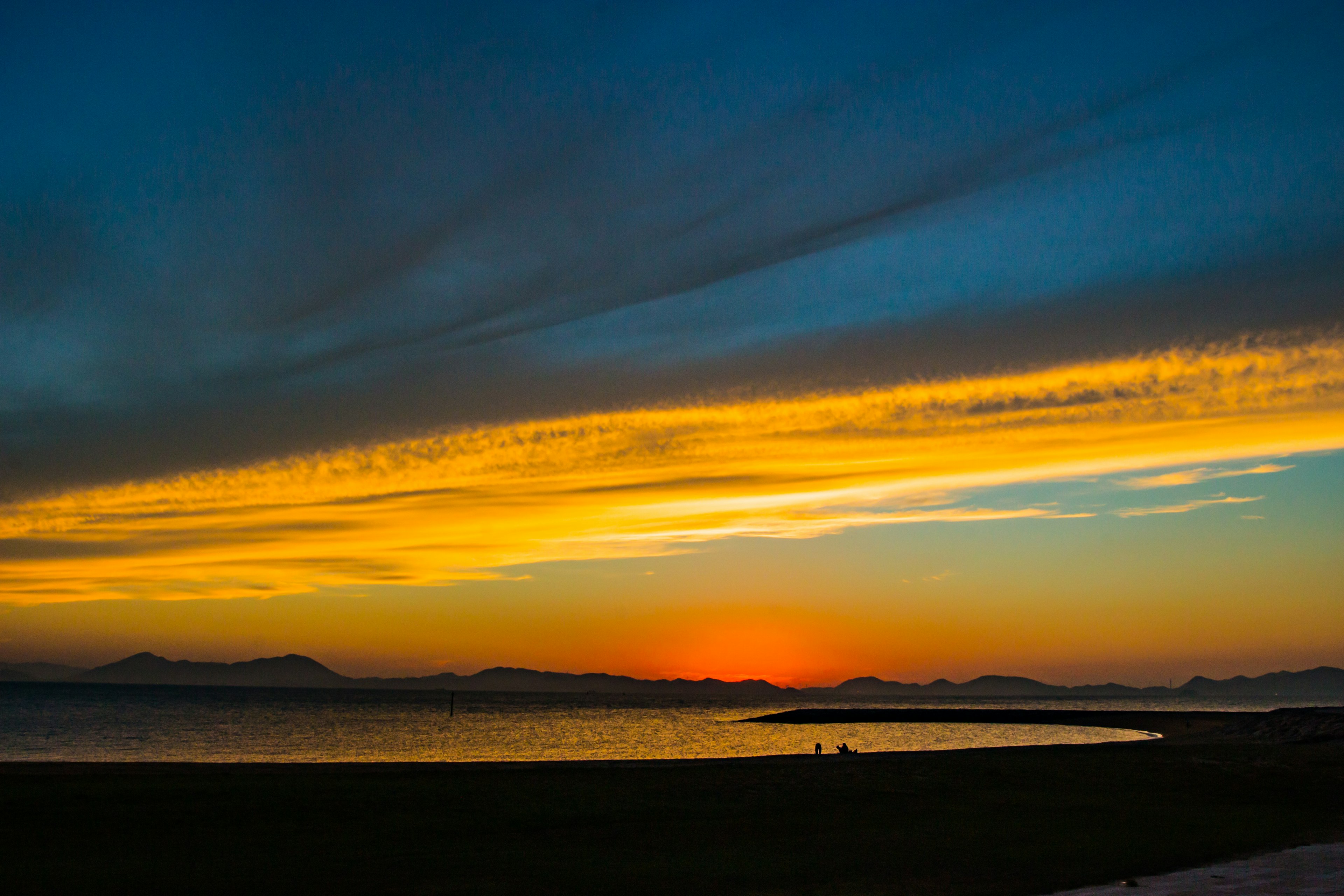 Coucher de soleil sur l'océan avec un ciel en dégradé orange et bleu vibrant