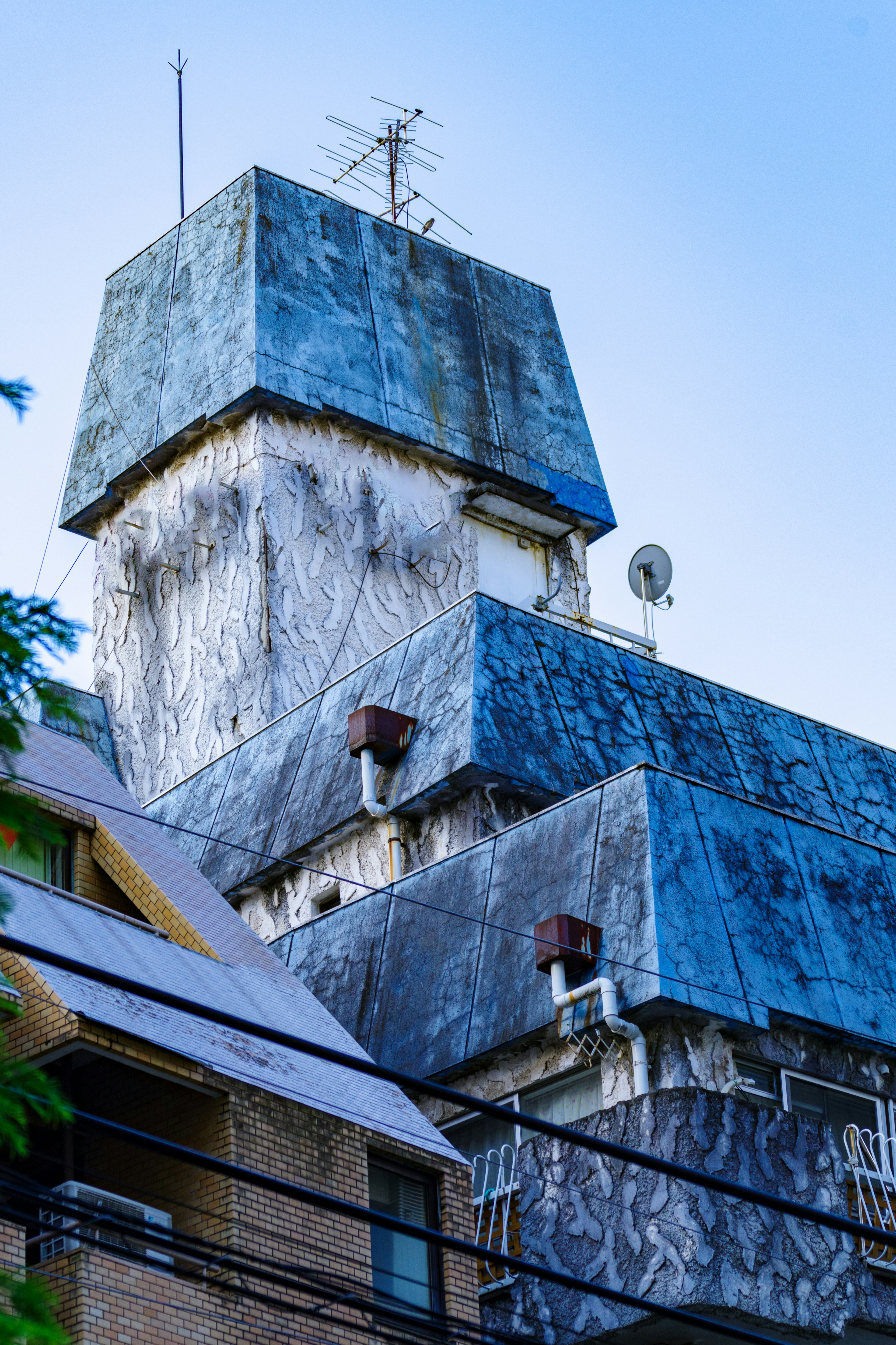 Bâtiment unique avec un toit bleu contrastant avec les structures environnantes