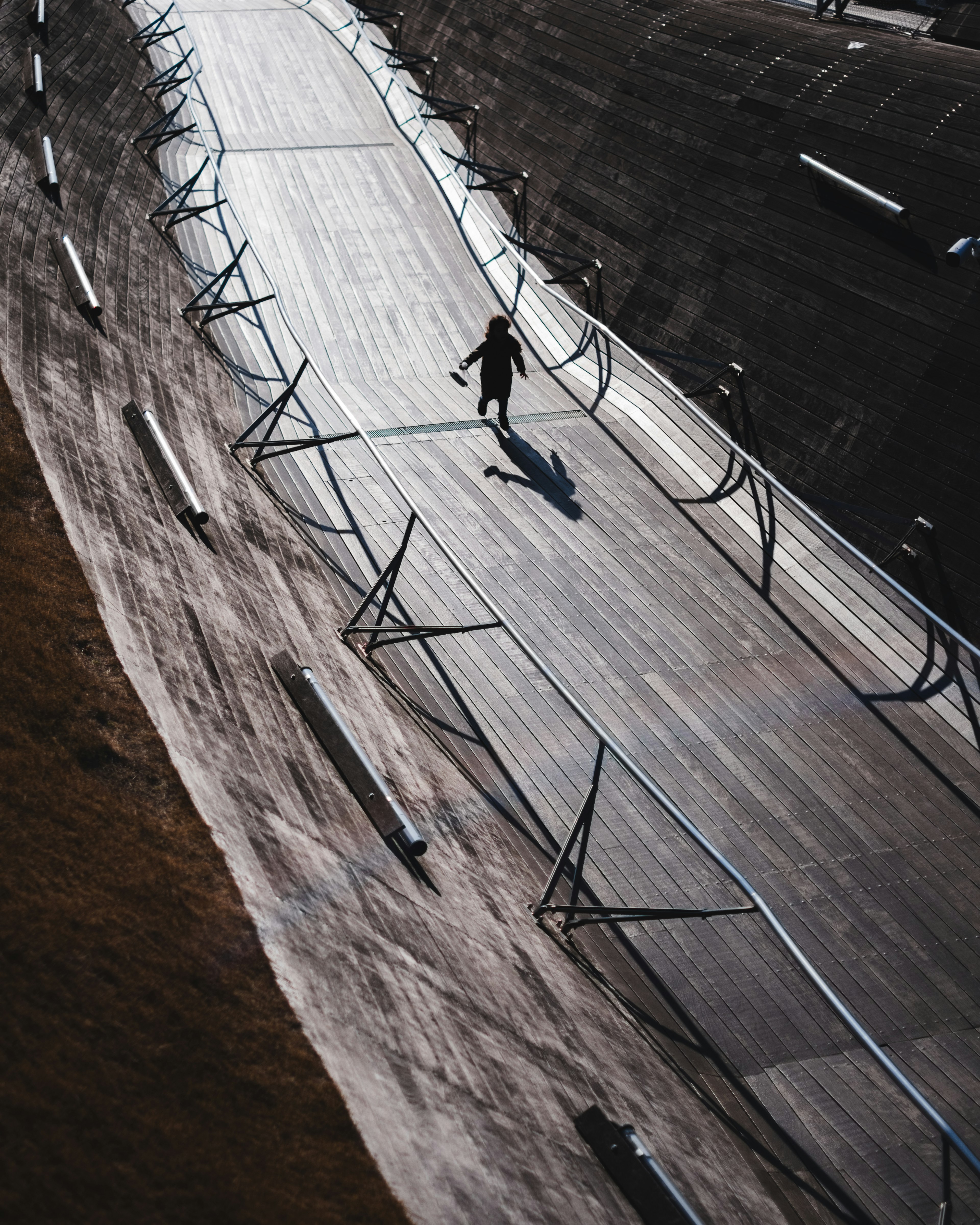 Silhouette of a person walking on a curved track with railings