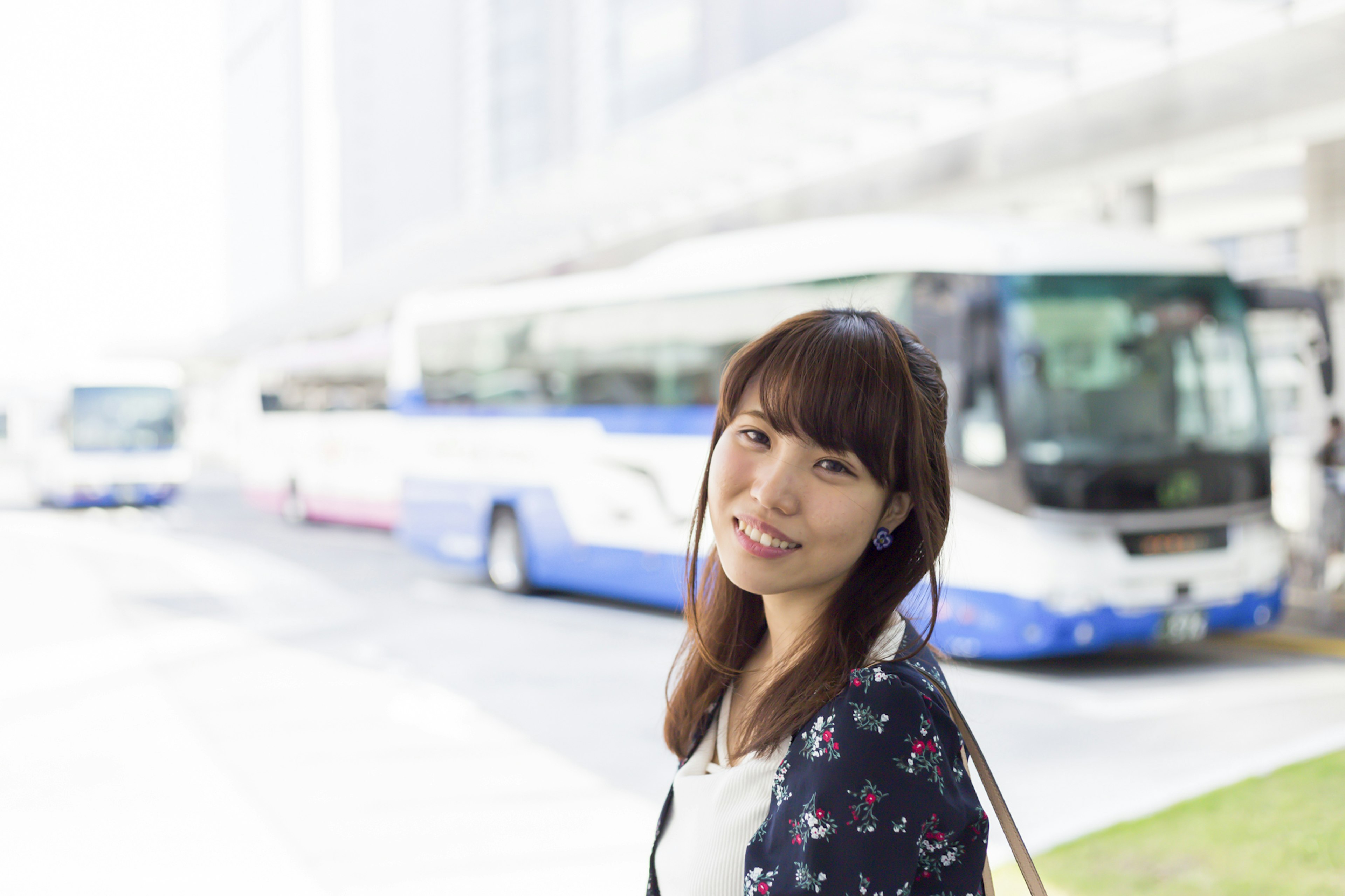 Una mujer sonriendo frente a autobuses en una estación