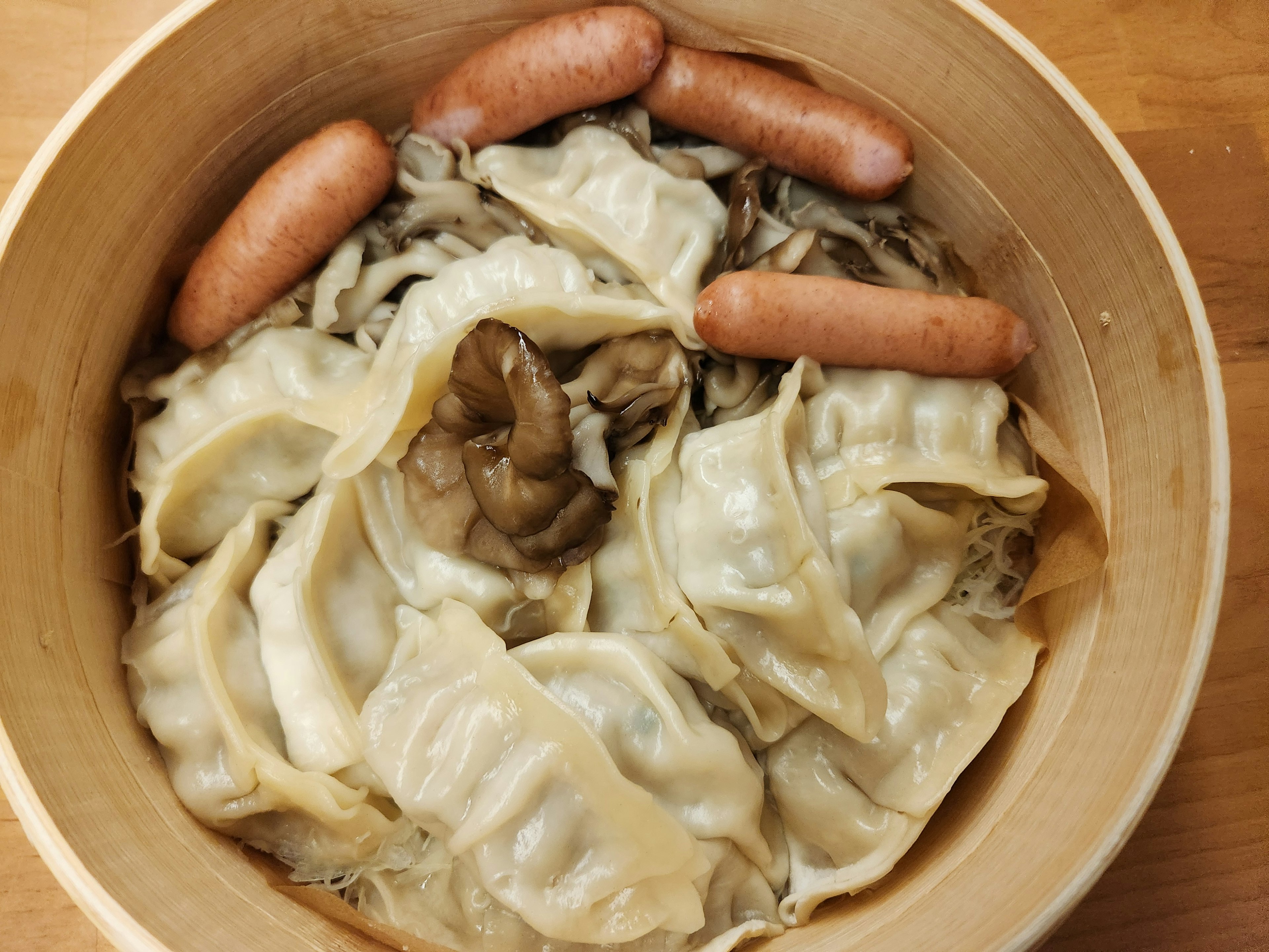 Dish of dumplings and sausages served in a wooden bowl