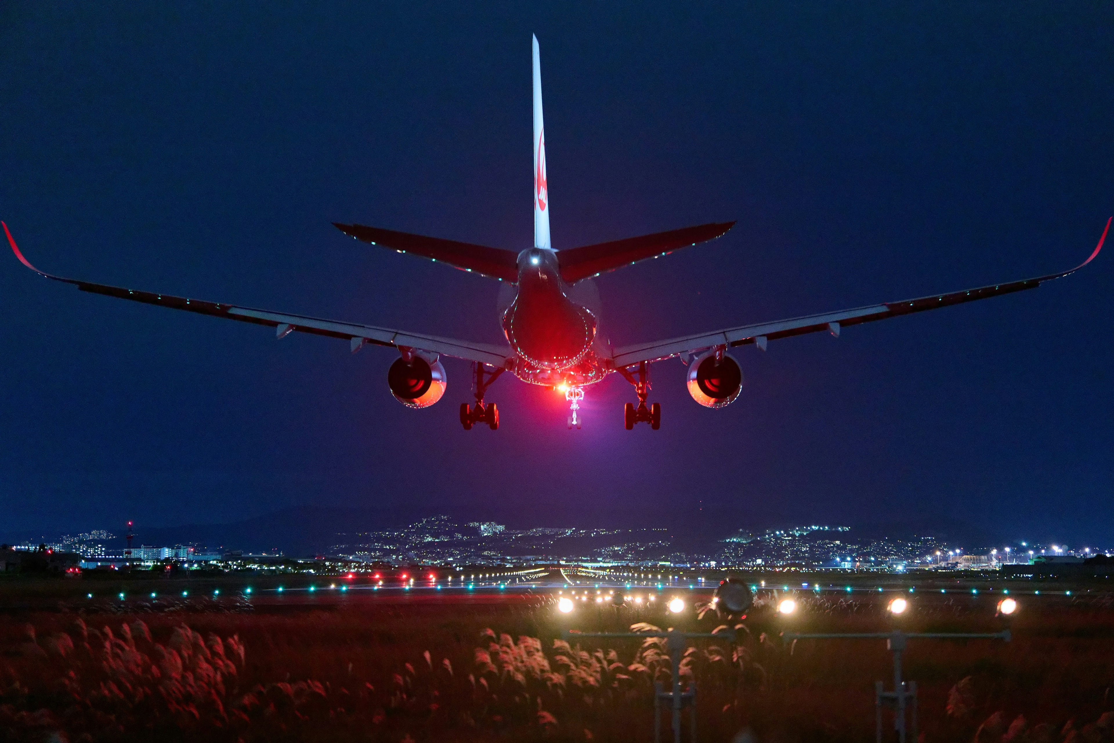 夜空に浮かぶ航空機の後方からの視点 輝く都市の光が背景に広がる