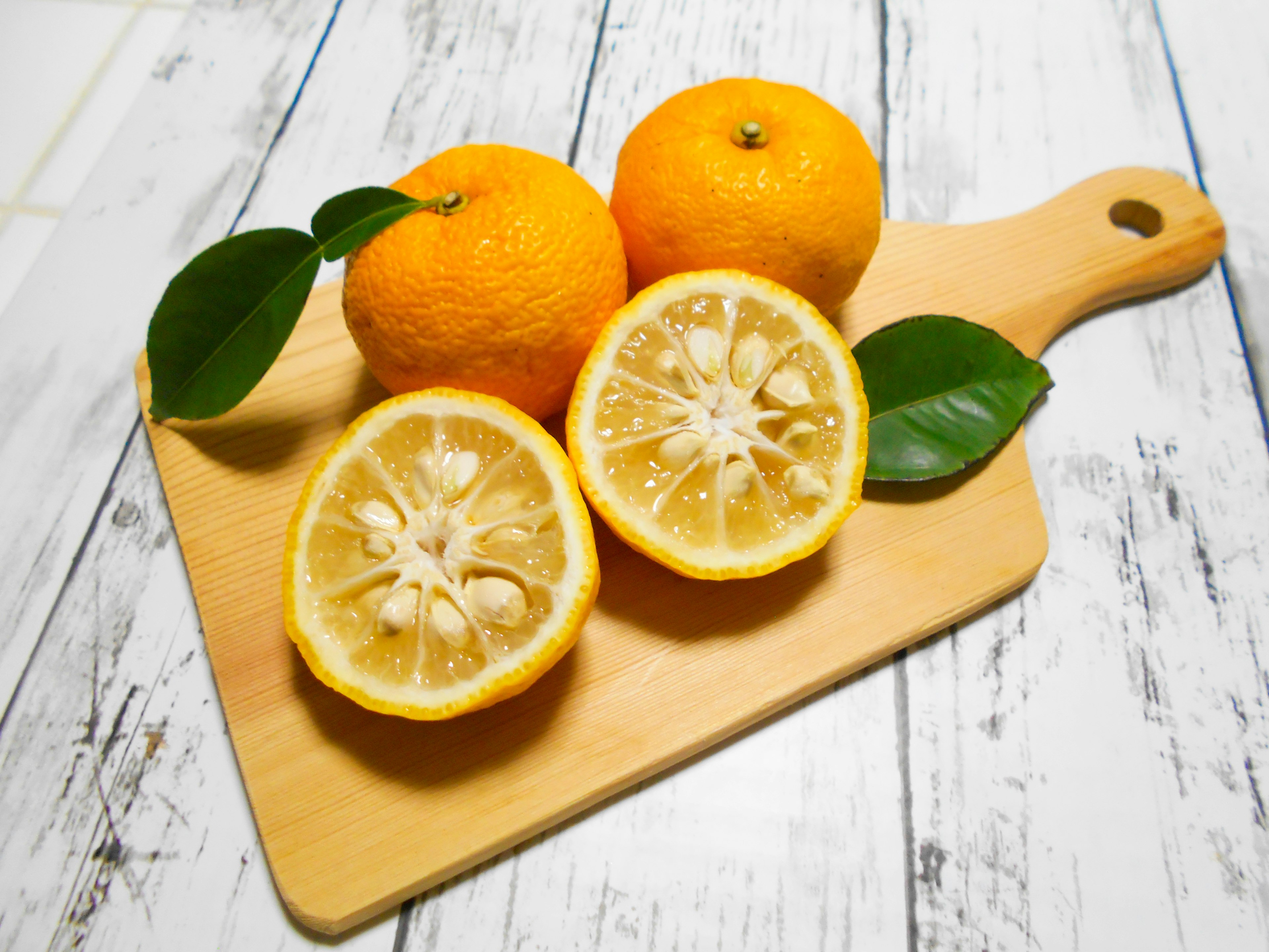 Oranges and sliced lemon on a wooden cutting board